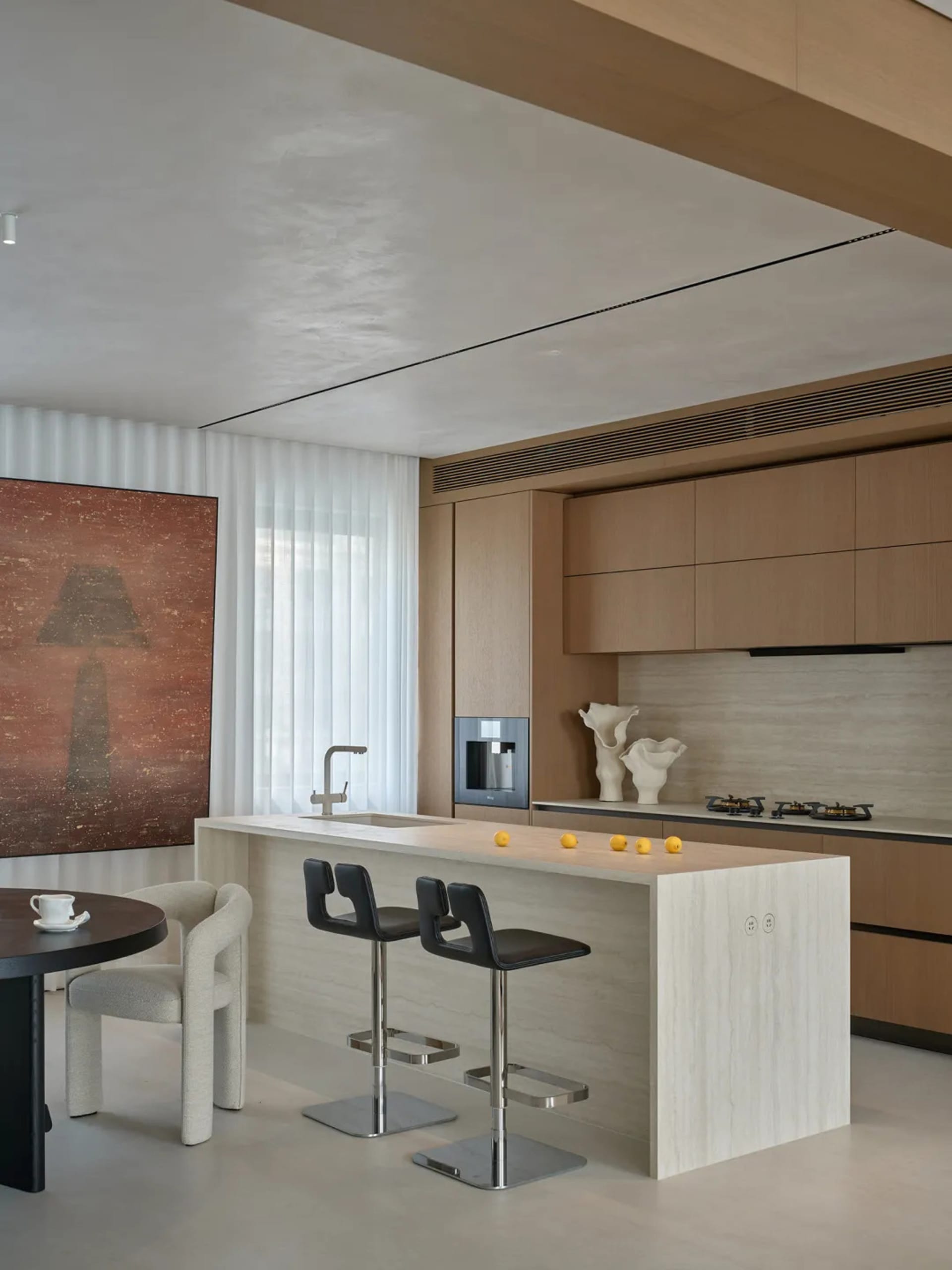 Modern kitchen with a large island, marble countertops, wooden cabinets, and a dining table, set in a well-lit space with a bright and inviting atmosphere