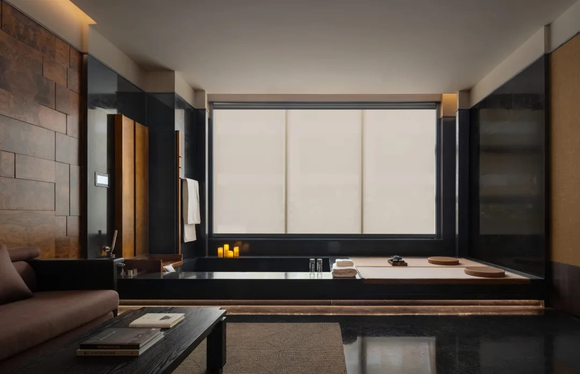 Modern bathroom with a black bathtub, window, and mirror, featuring a clean and minimalist design with natural light and a sense of depth