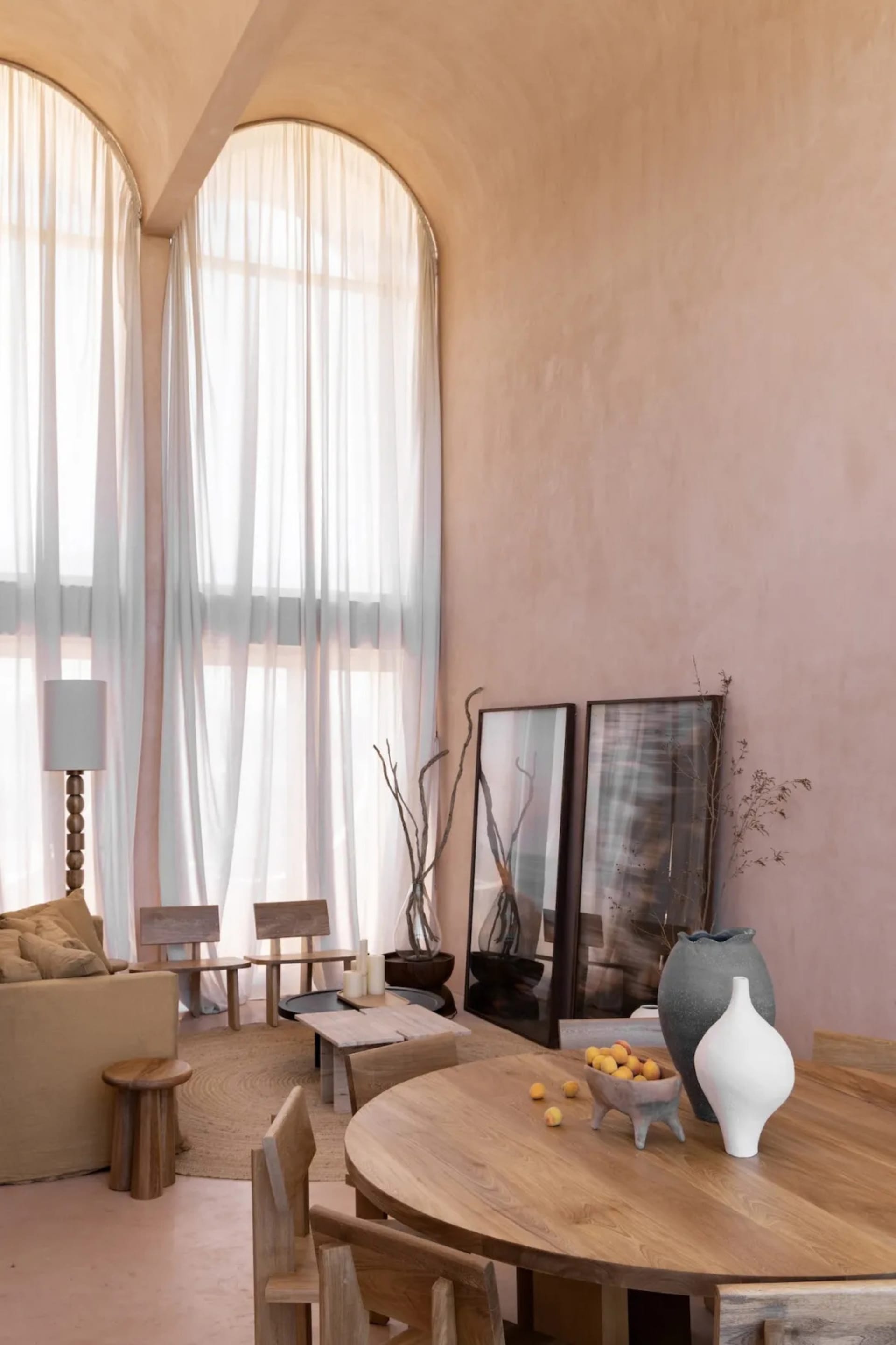 Comfortable living space with a couch, dining table, and chair, filled with natural light from a large window and decorated with a vase, bowl, and potted plant
