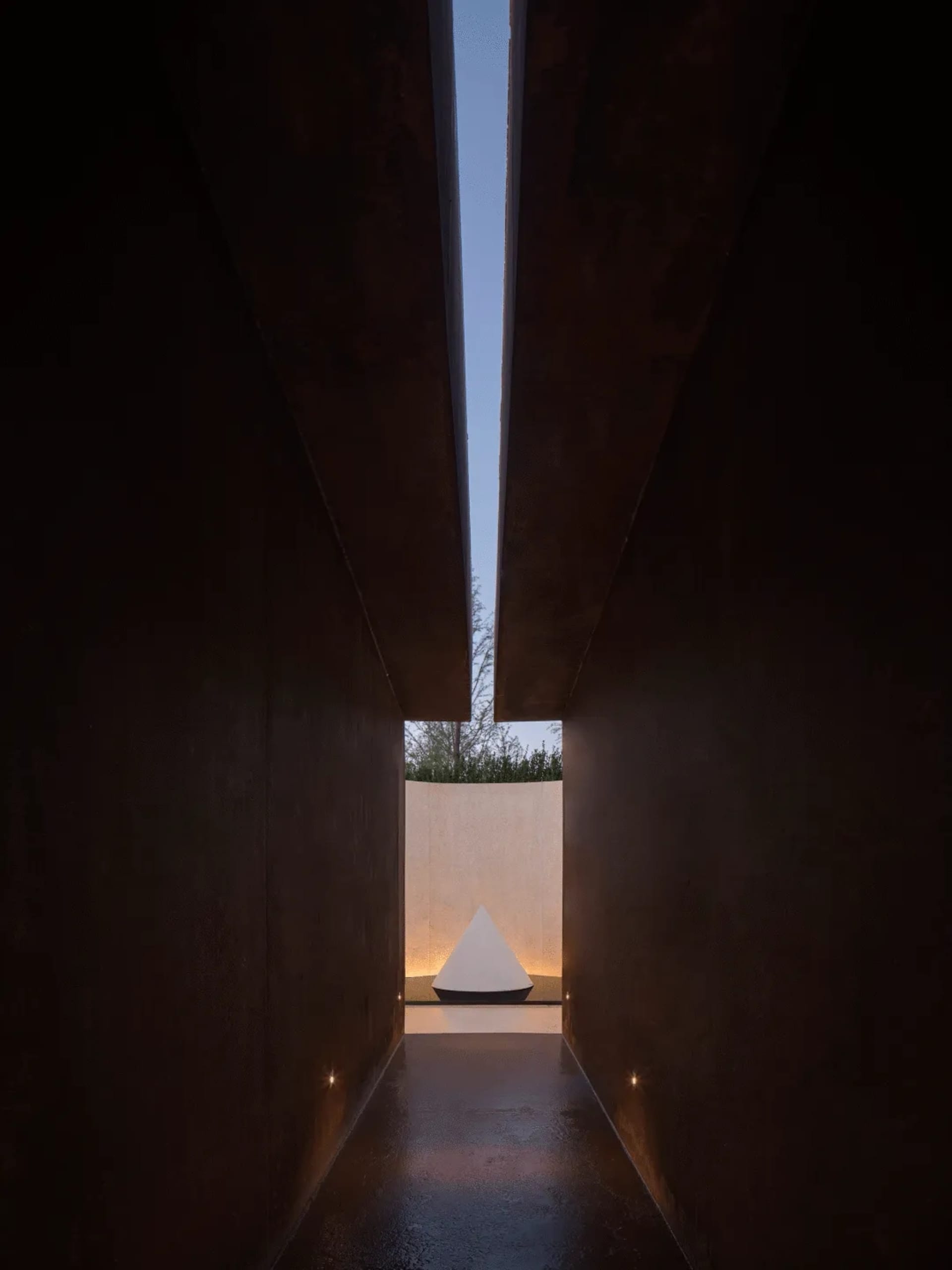A dark room with a small white triangle on the floor, creating a focal point in the space