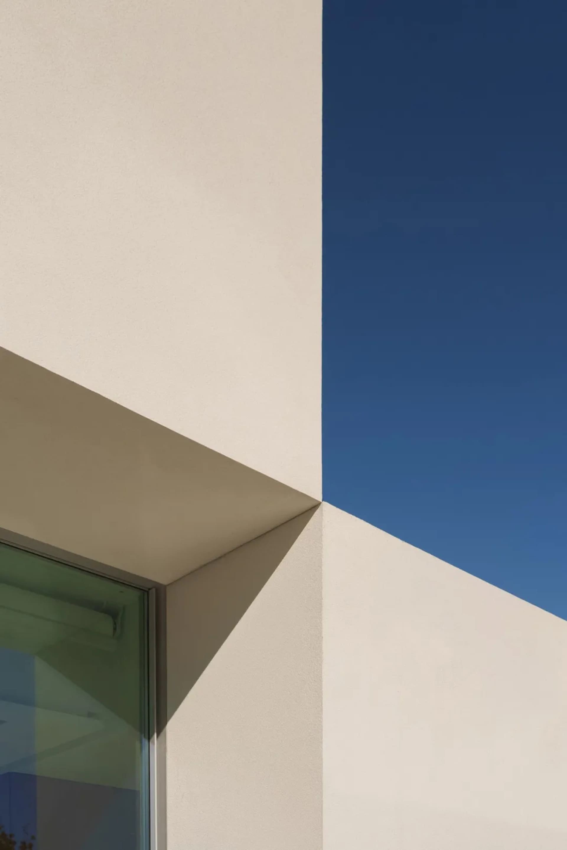 Photograph of a modern building with a white exterior, a large white triangle feature, and sunlight shining on the building