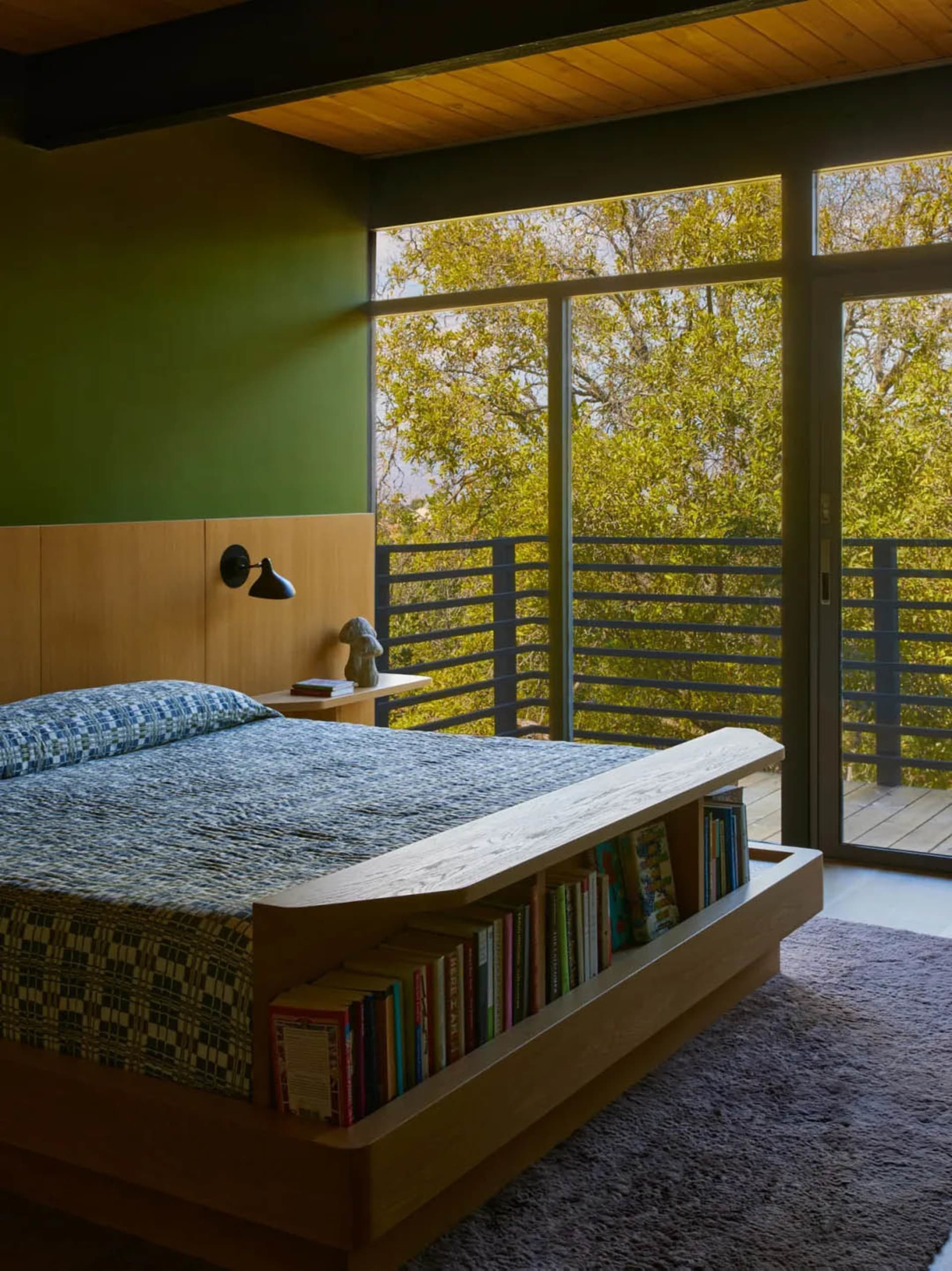 Cozy bedroom with a white bed, a brown bookshelf, and a window above the bed, providing natural light