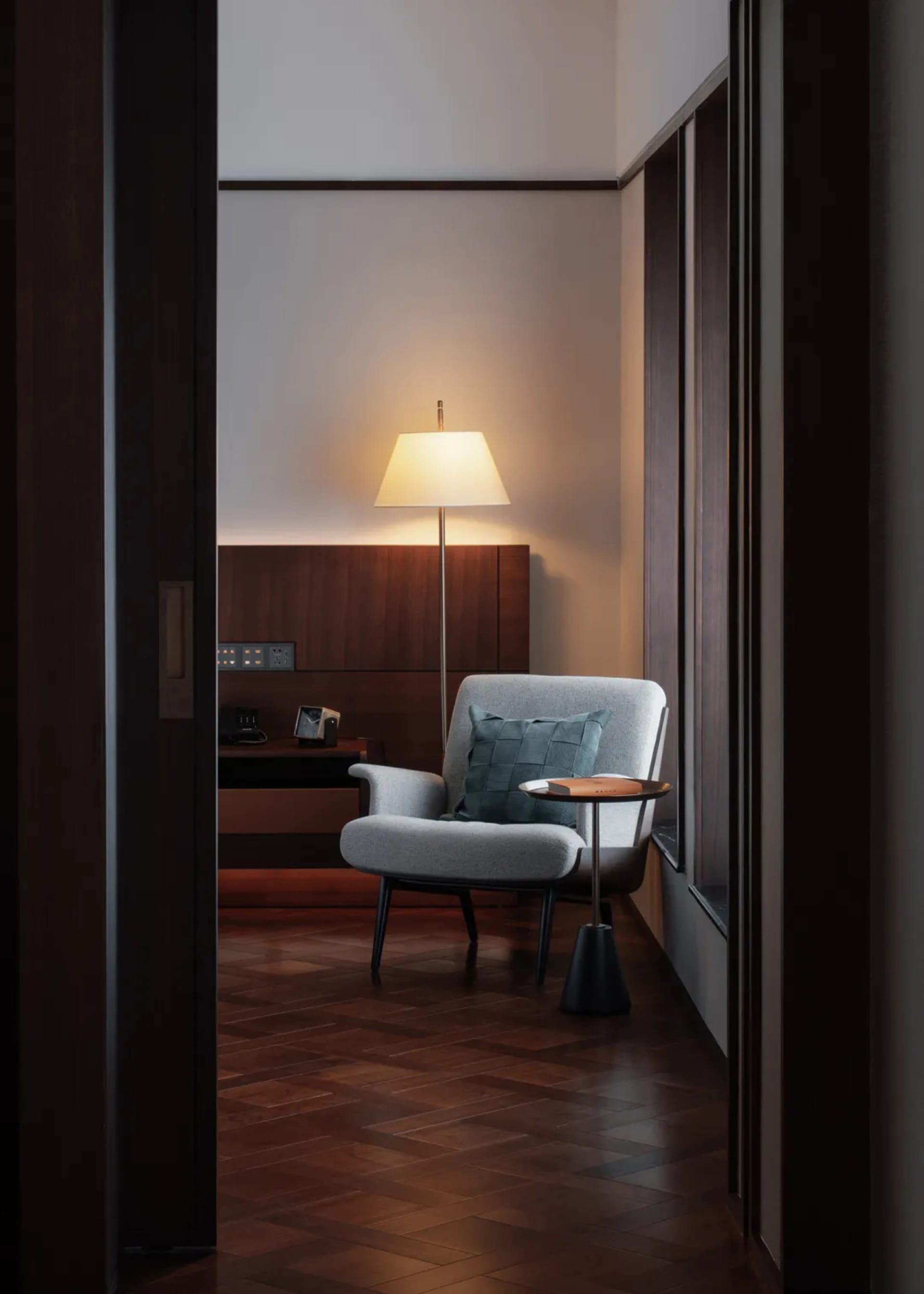 Cozy modern living space with a gray chair and black lamp, dimly lit with warm ambiance