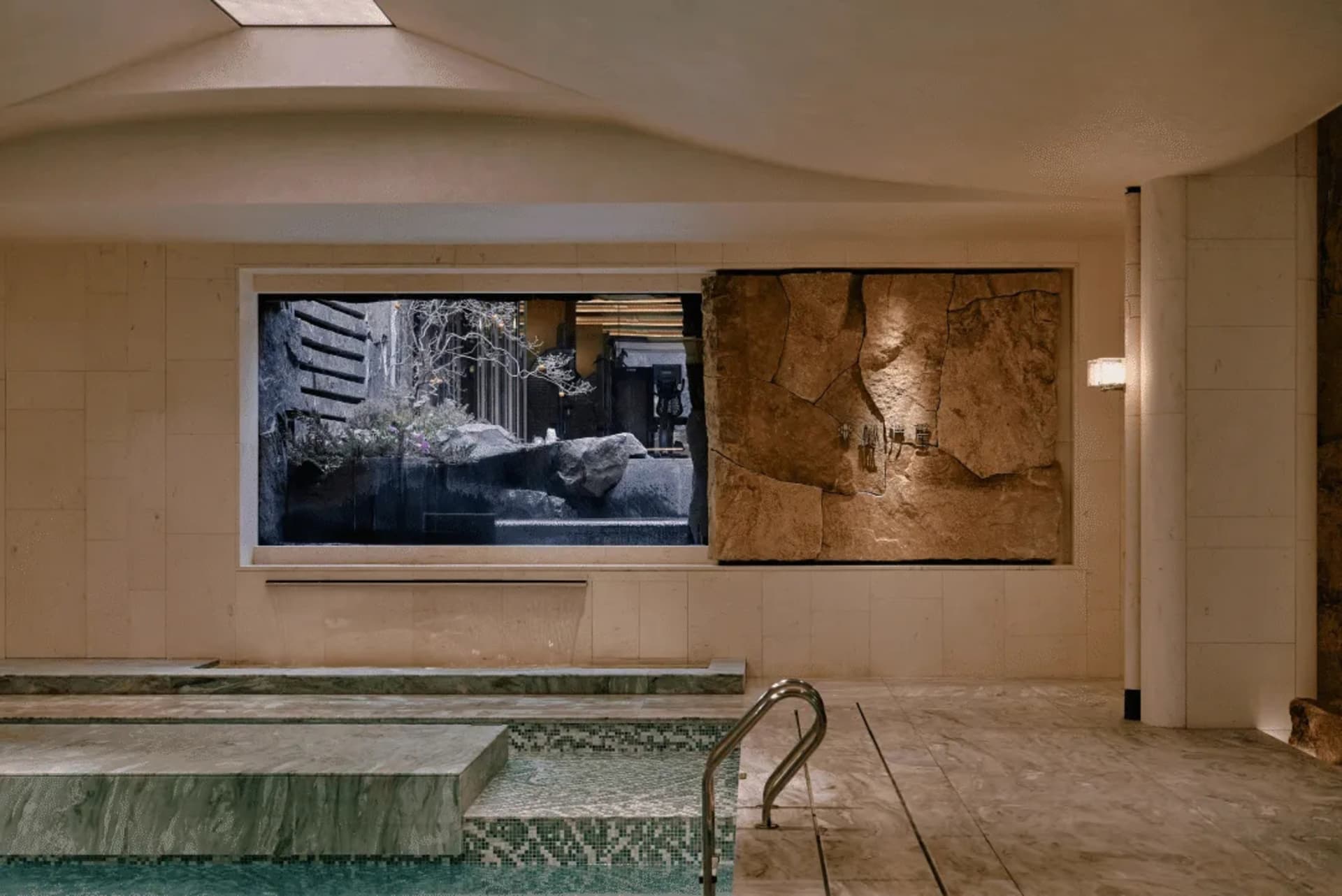 Bathroom with a large window, a pool, and a stone wall, featuring modern design and natural light