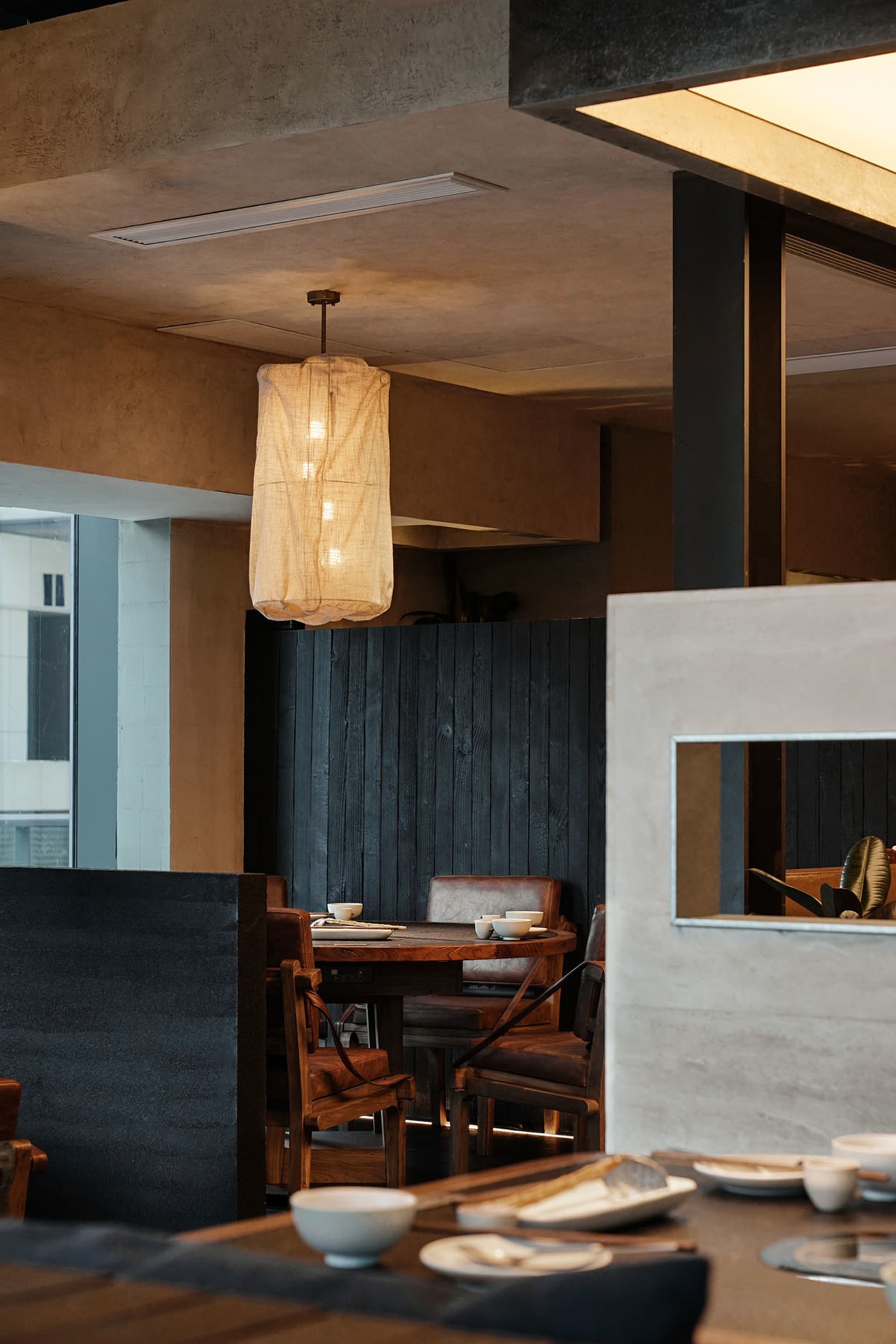 A cozy restaurant with a dining table and chairs, surrounded by wood and fabric, with a dimly lit atmosphere