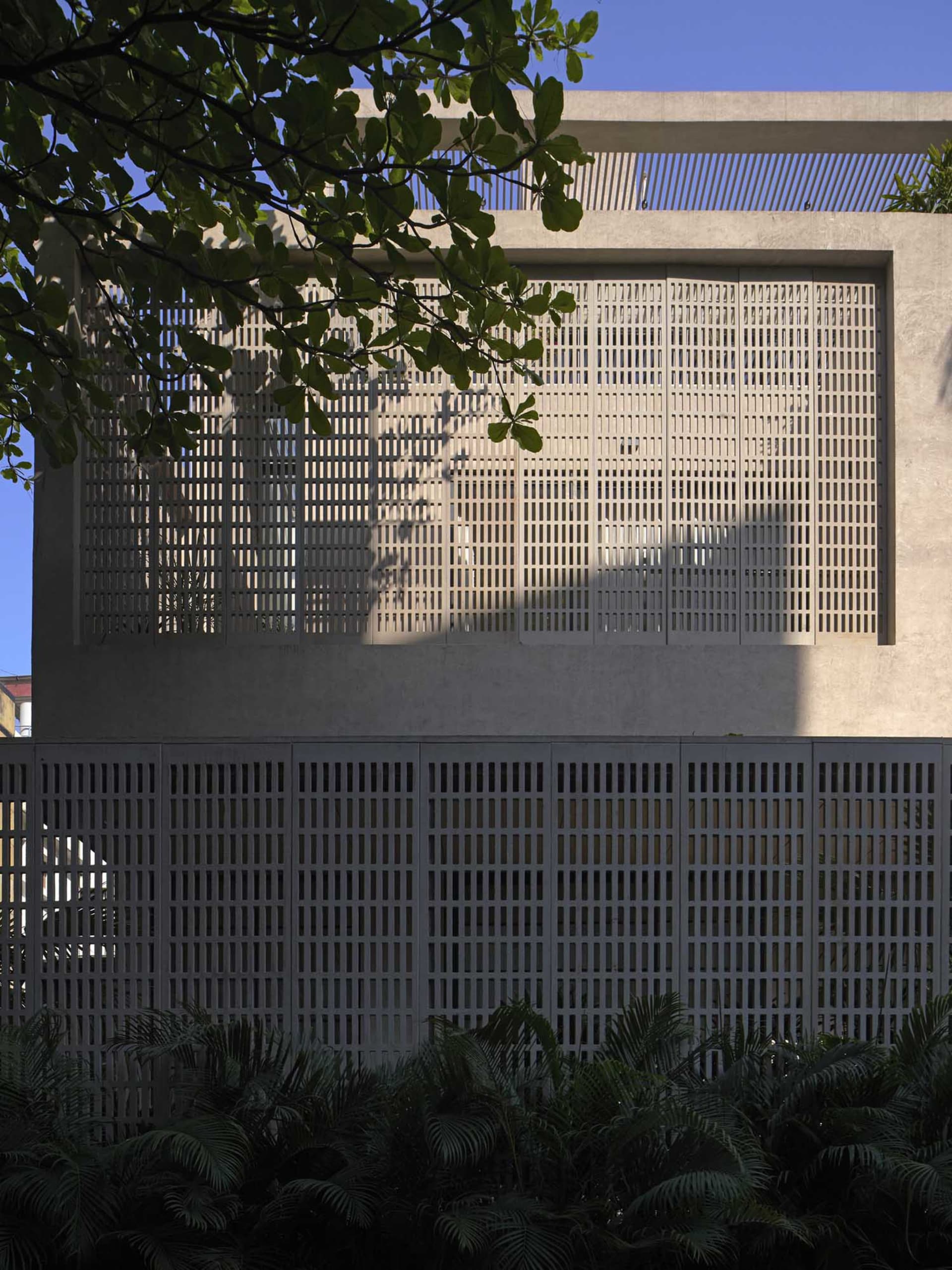 Photograph of a concrete building with a grid pattern on the wall and a window on the side, set against a natural outdoor backdrop