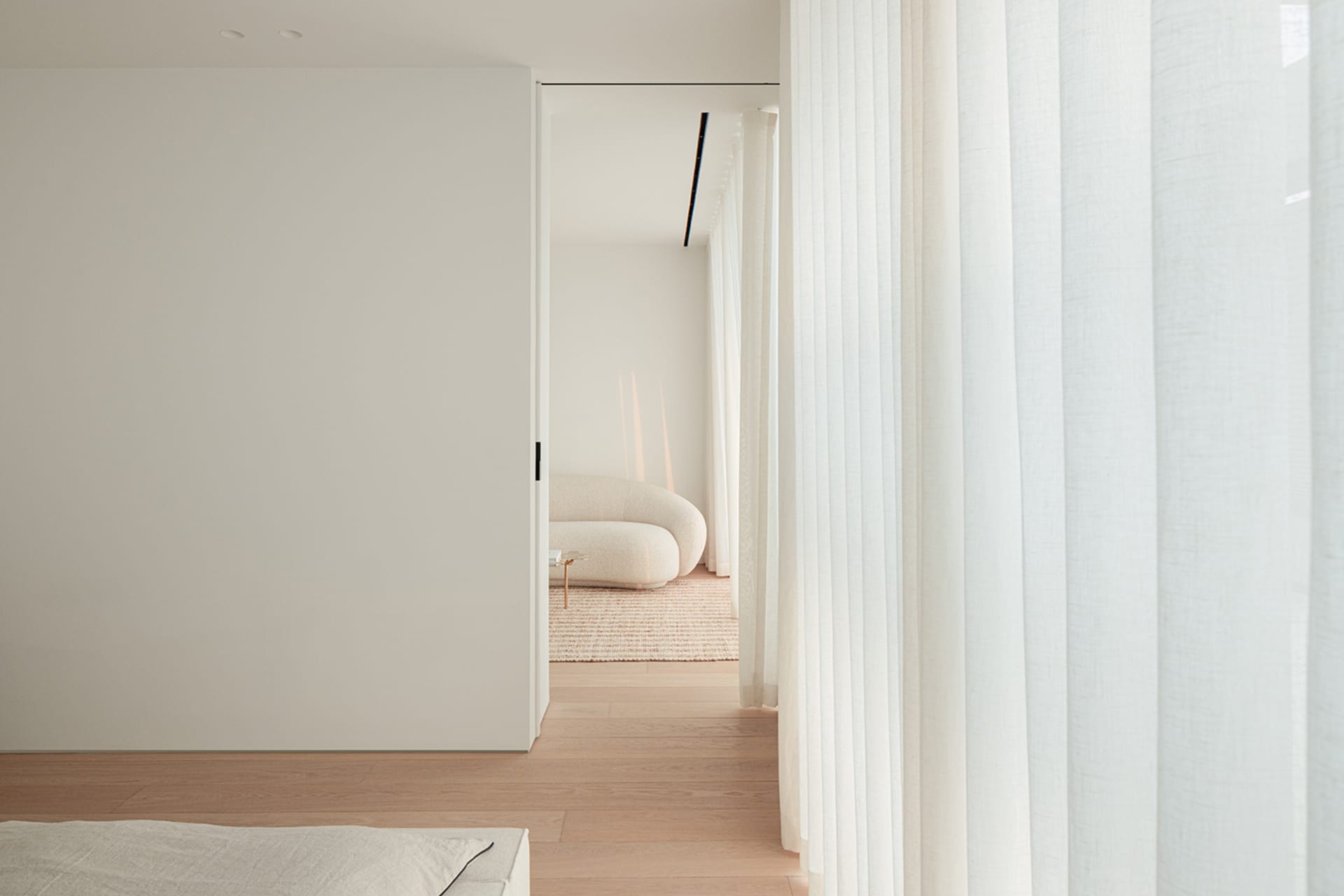 A modern living room with a white color scheme, natural light, and comfortable seating options