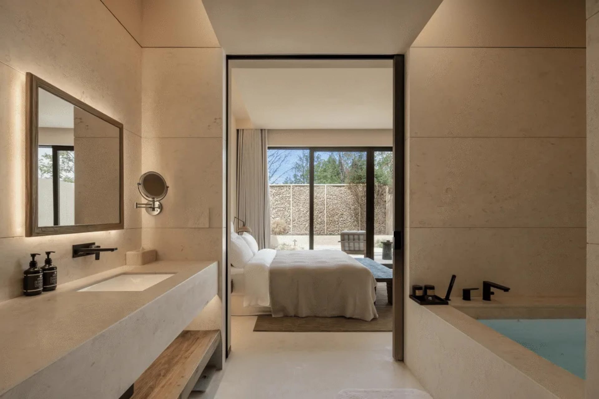A modern minimalist bedroom with a bed, sink, and door, featuring predominantly white surfaces and a clean appearance