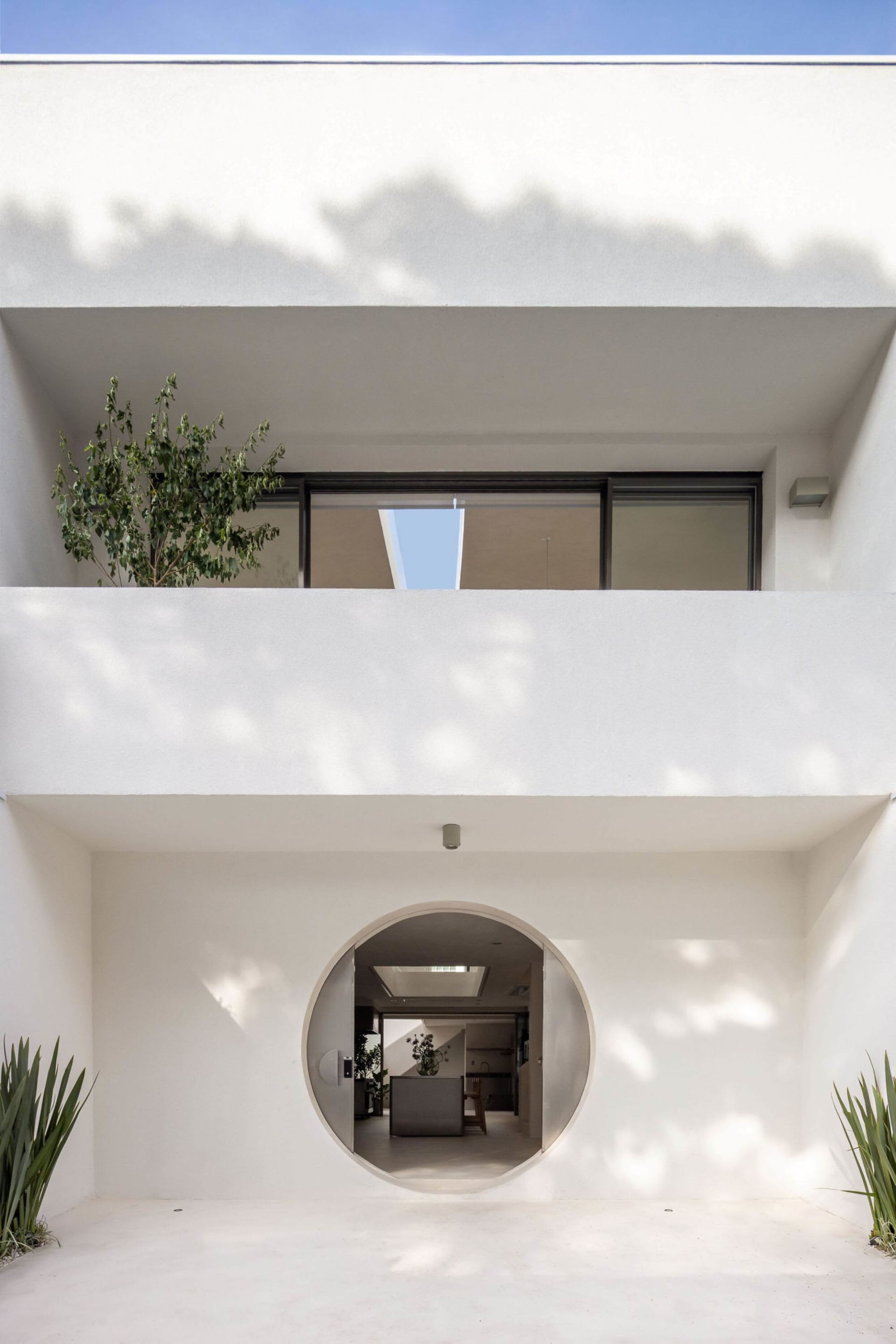 A bright and inviting living room with a modern house featuring a circular window and a potted plant, well-lit with a warm atmosphere