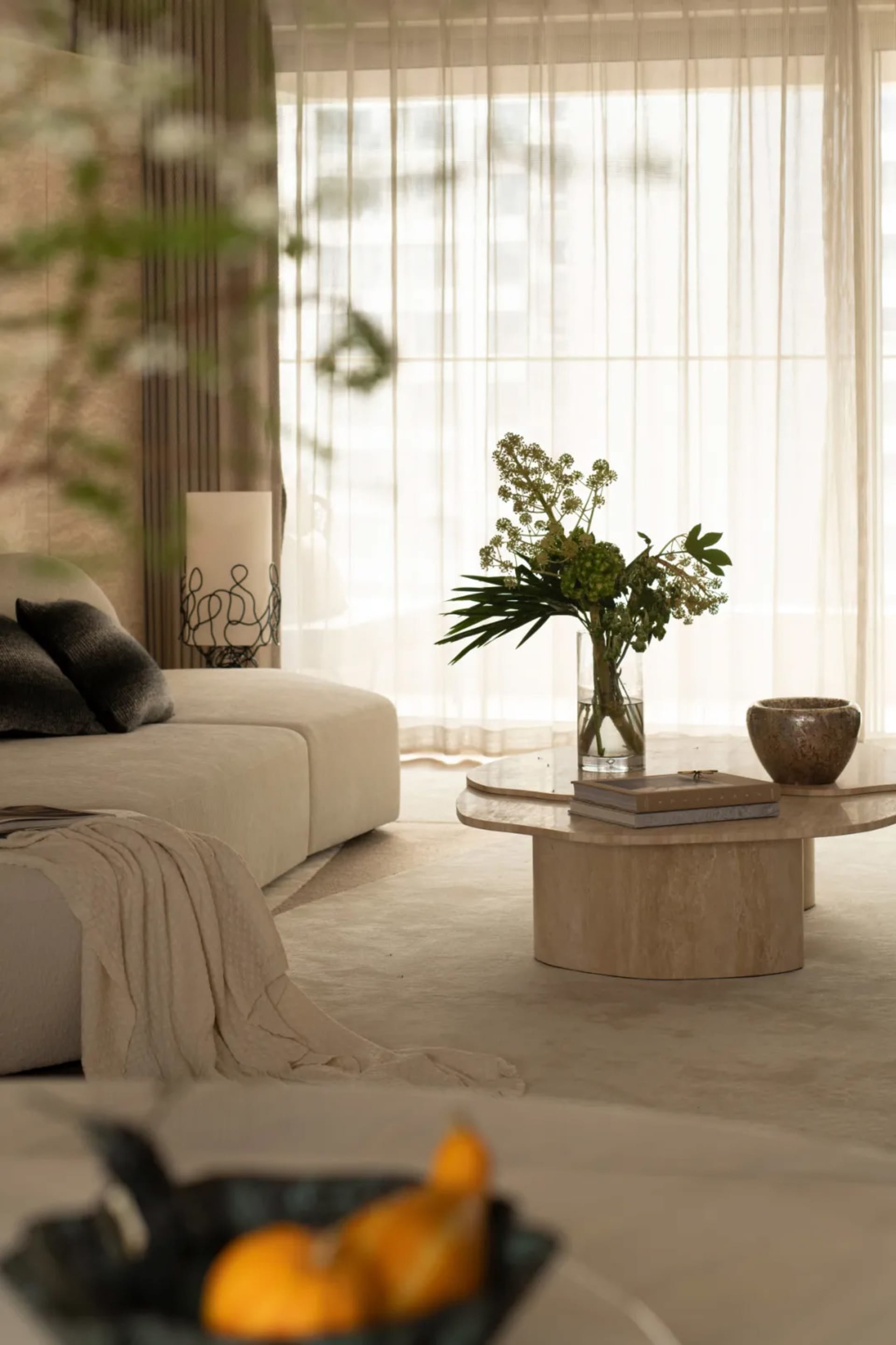A well-lit living room with a white couch, coffee table, and a vase with flowers, showcasing modern simplicity and functionality