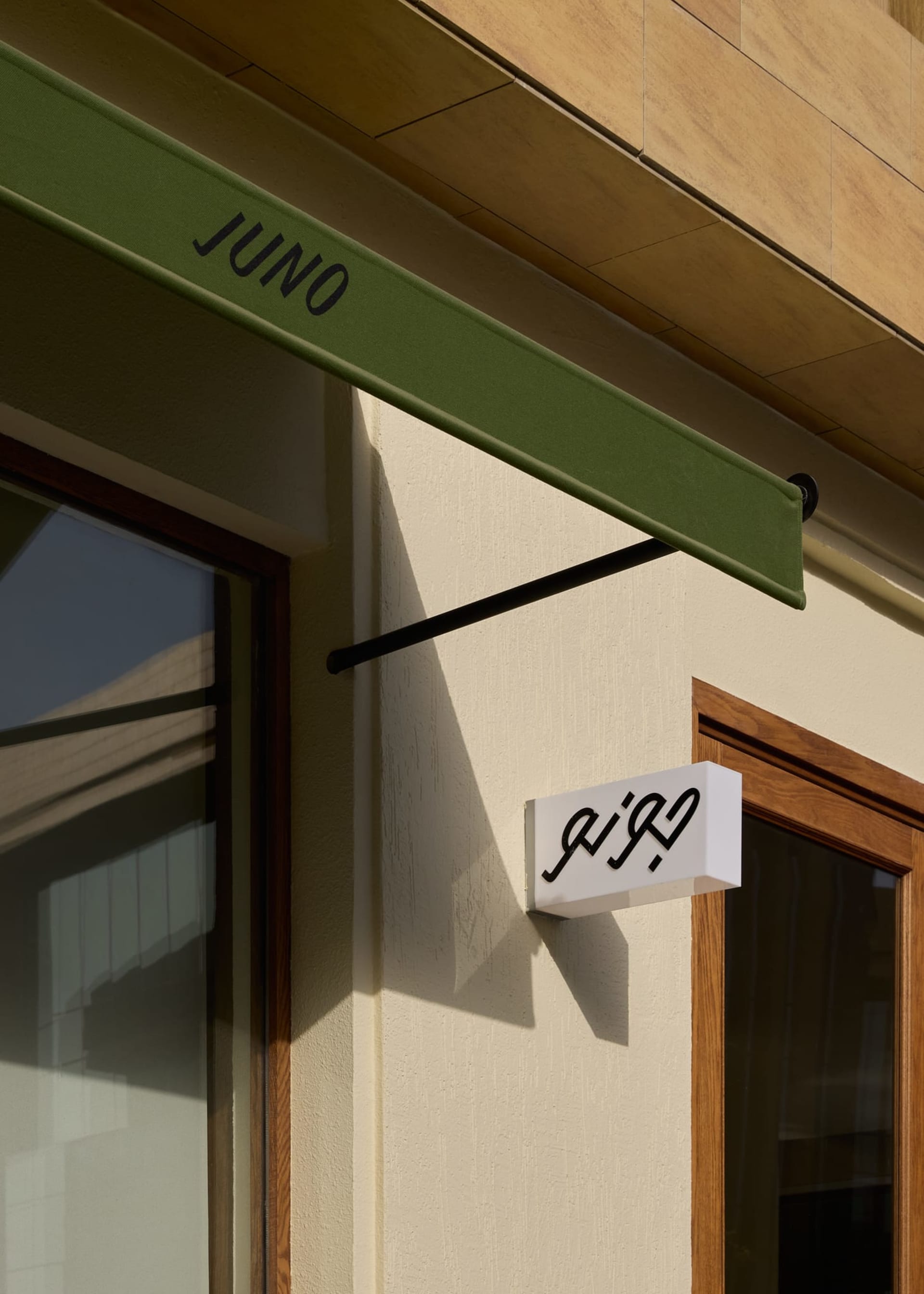 A photograph of a store with a green awning and white sign, set against a brown wooden exterior in a typical urban setting
