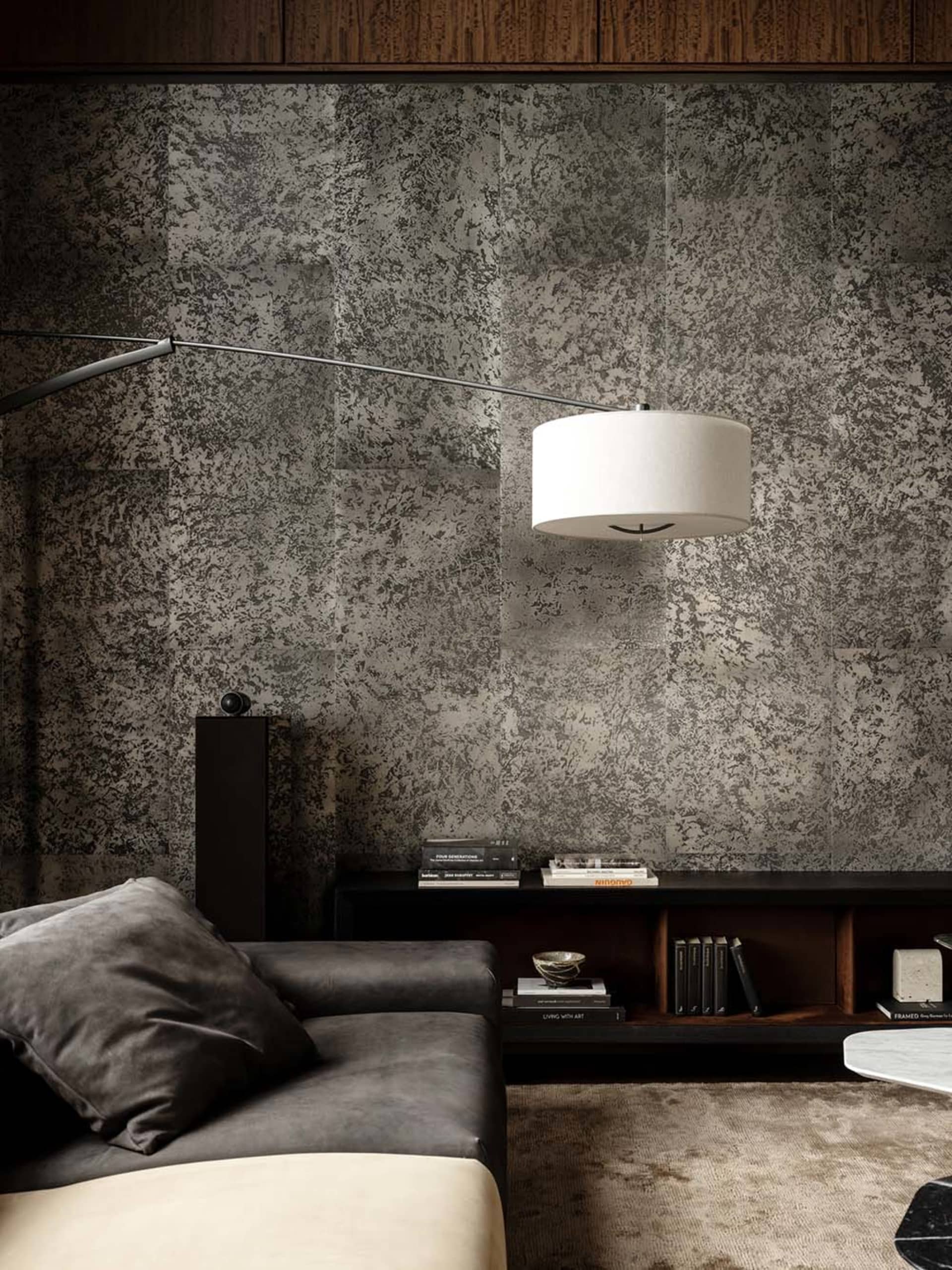 Cozy living room with a gray couch, a table lamp, and a bookshelf filled with books, set in a well-lit space