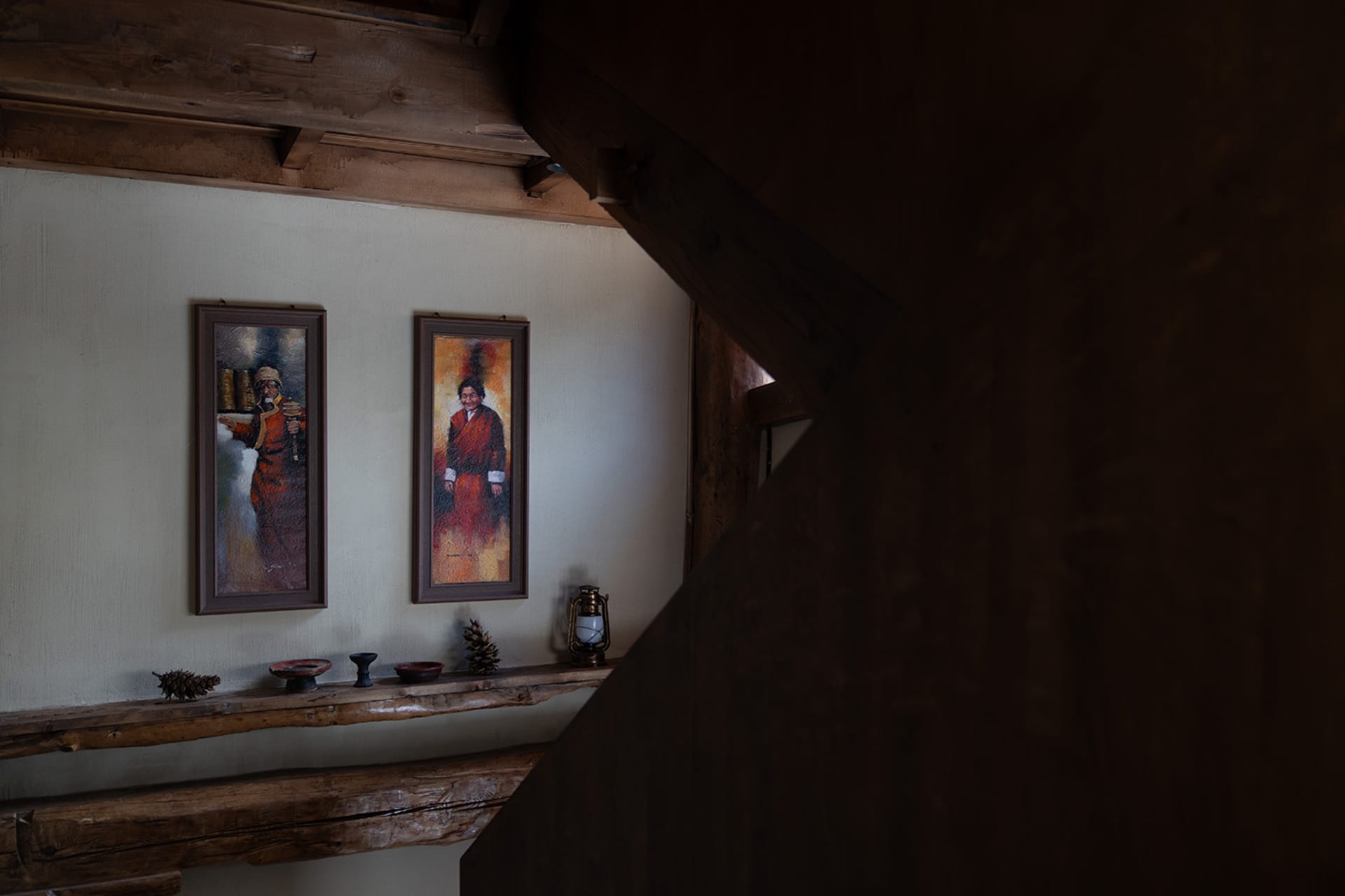 Cozy living space with a wooden floor, wooden staircase, and rustic decor, featuring a painting and decorative items on a shelf
