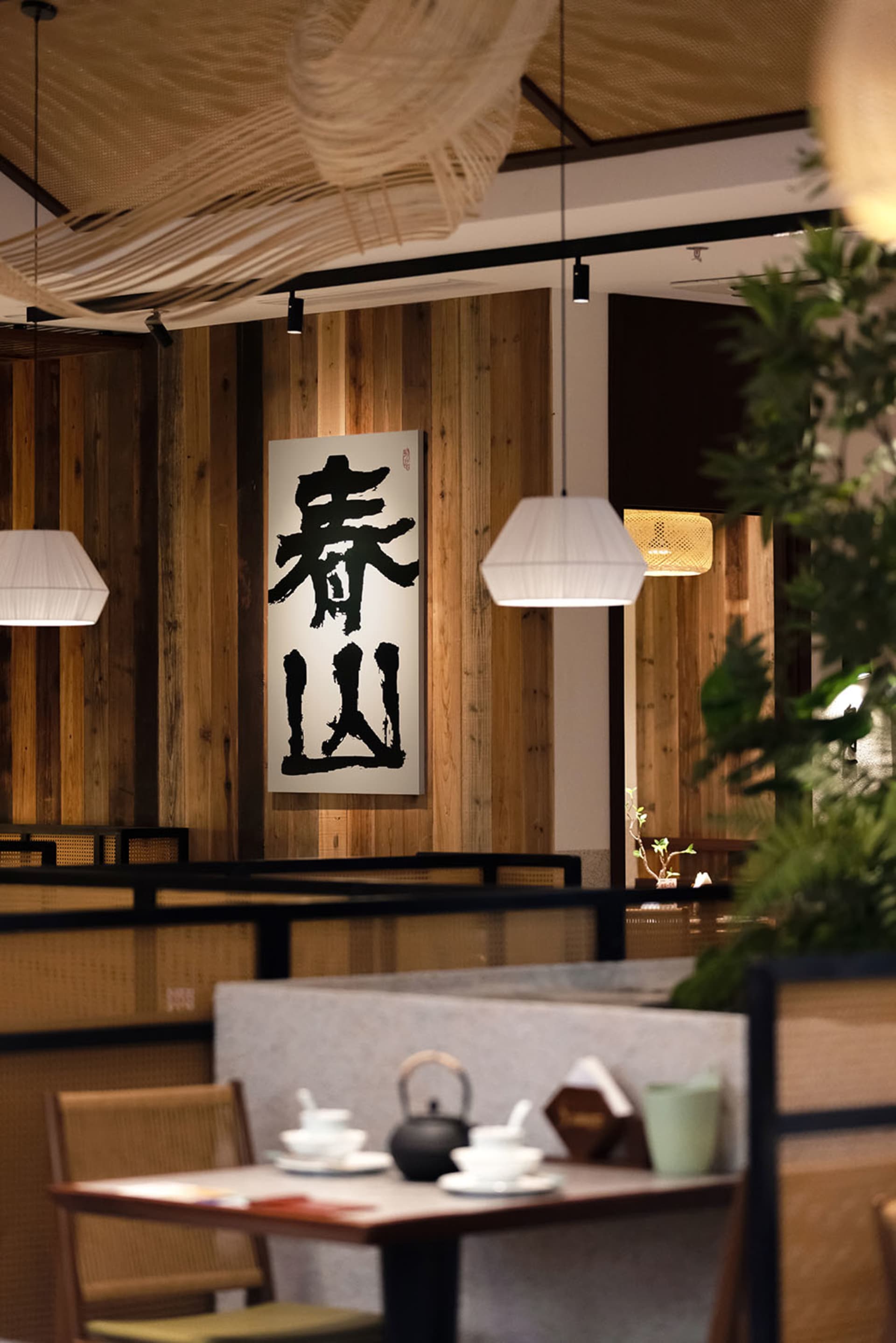 A modern restaurant interior with wooden panel walls, well-lit and inviting, featuring tables and chairs for social dining
