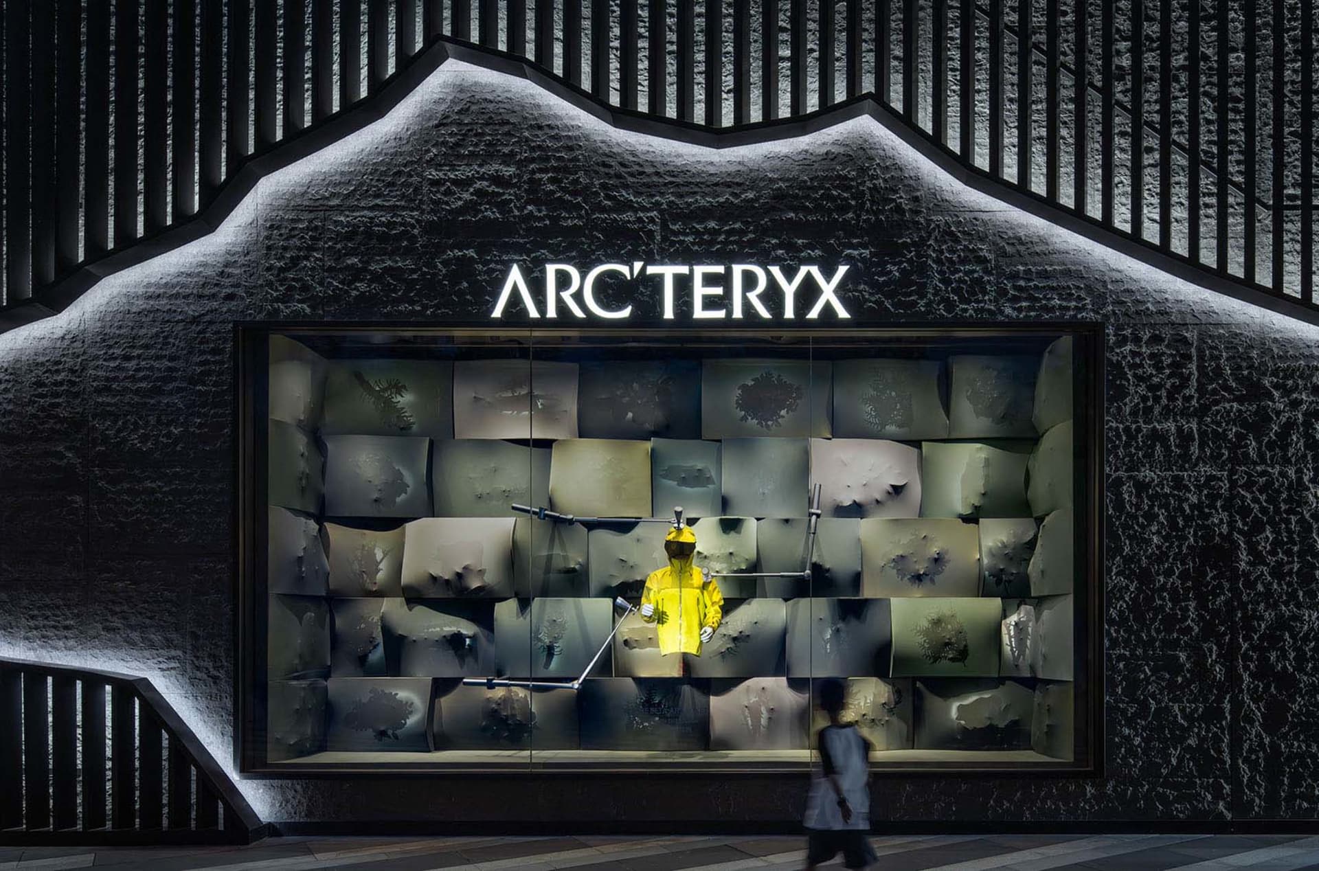 A storefront window display featuring a mannequin in a yellow jacket, surrounded by clothing and merchandise, creating an inviting atmosphere for potential customers