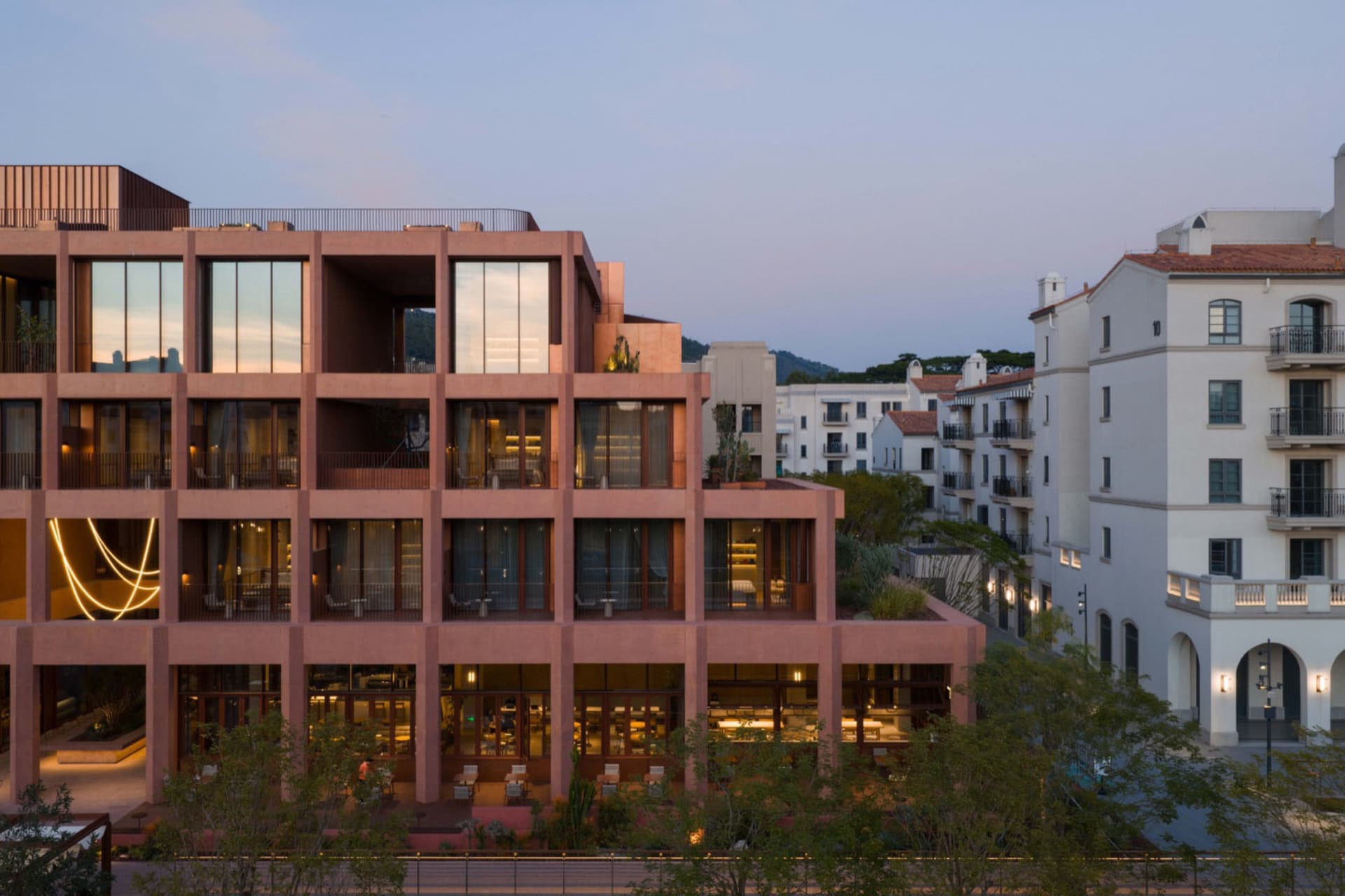 A large, well-lit building with a modern design, featuring a pink and brown color scheme and a mix of residential and commercial areas