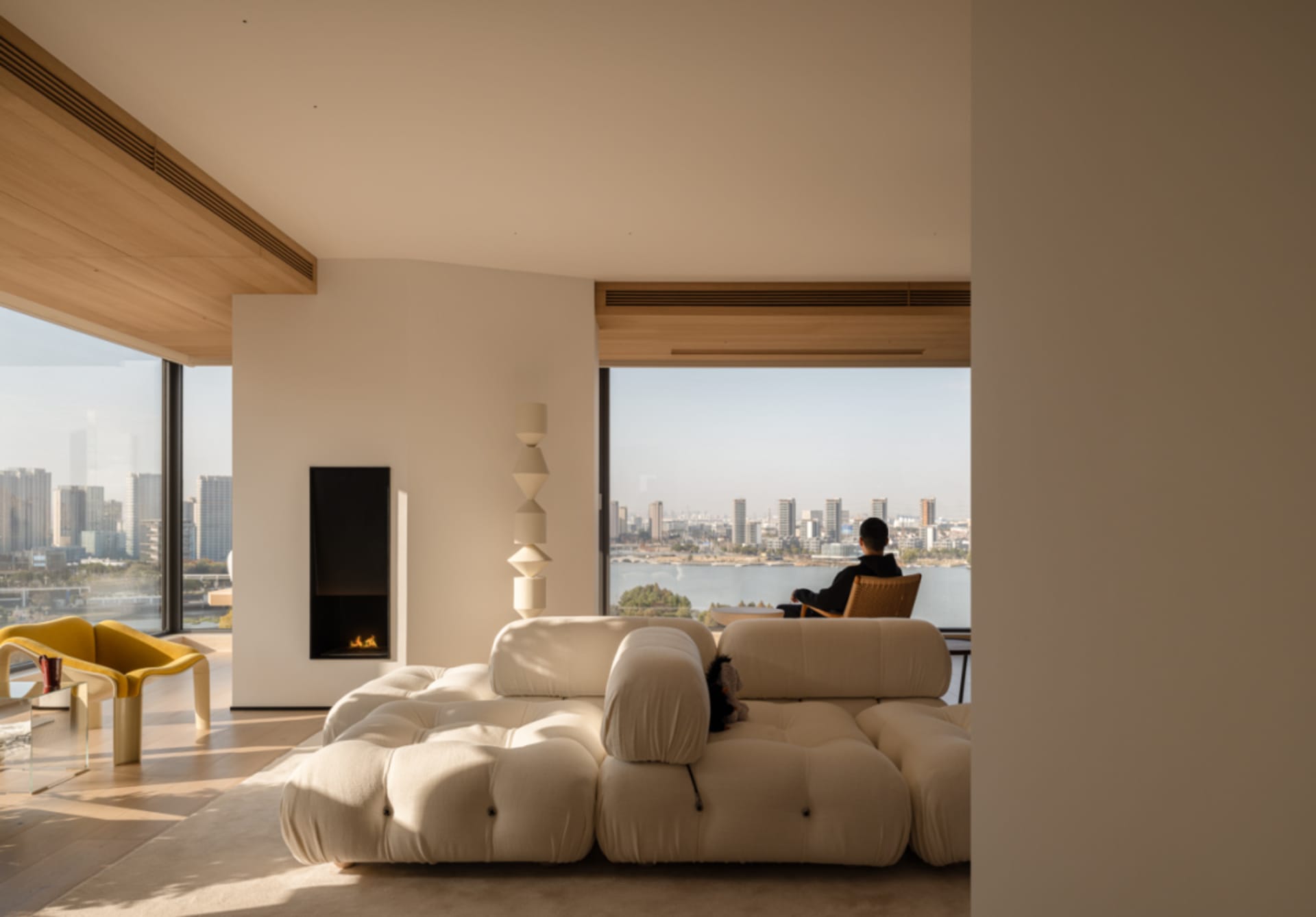 A modern living room with a white couch, a chair, and a fireplace, featuring clean lines and minimalistic design elements, with natural light streaming in through the windows