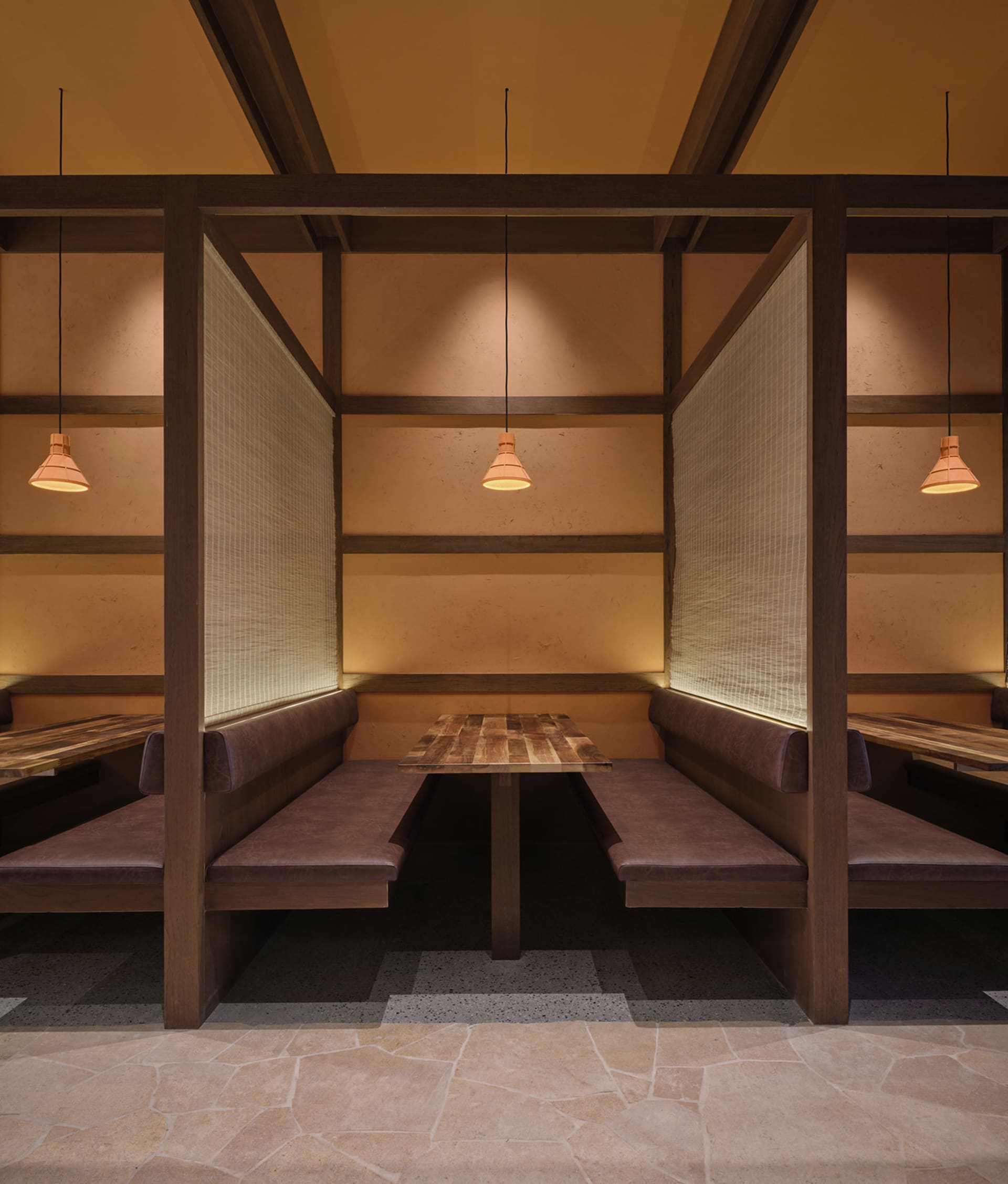 A modern restaurant with a wooden interior, featuring a dining area with tables and benches, a bar with a counter, and dim lighting creating a cozy ambiance