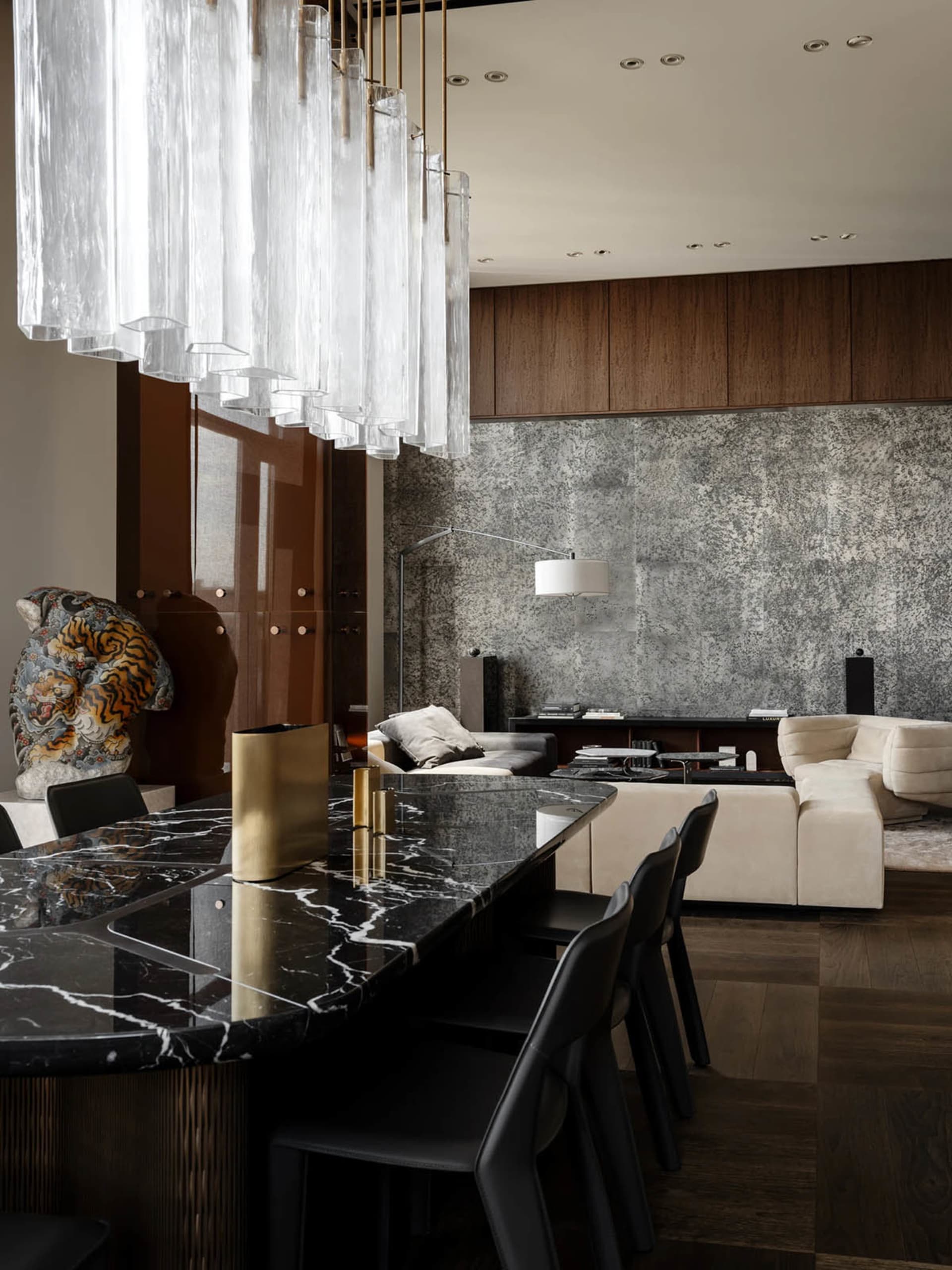 Cozy modern living room with a black marble countertop, a wooden floor, and a gold vase on display, featuring a couch, chair, and dining table
