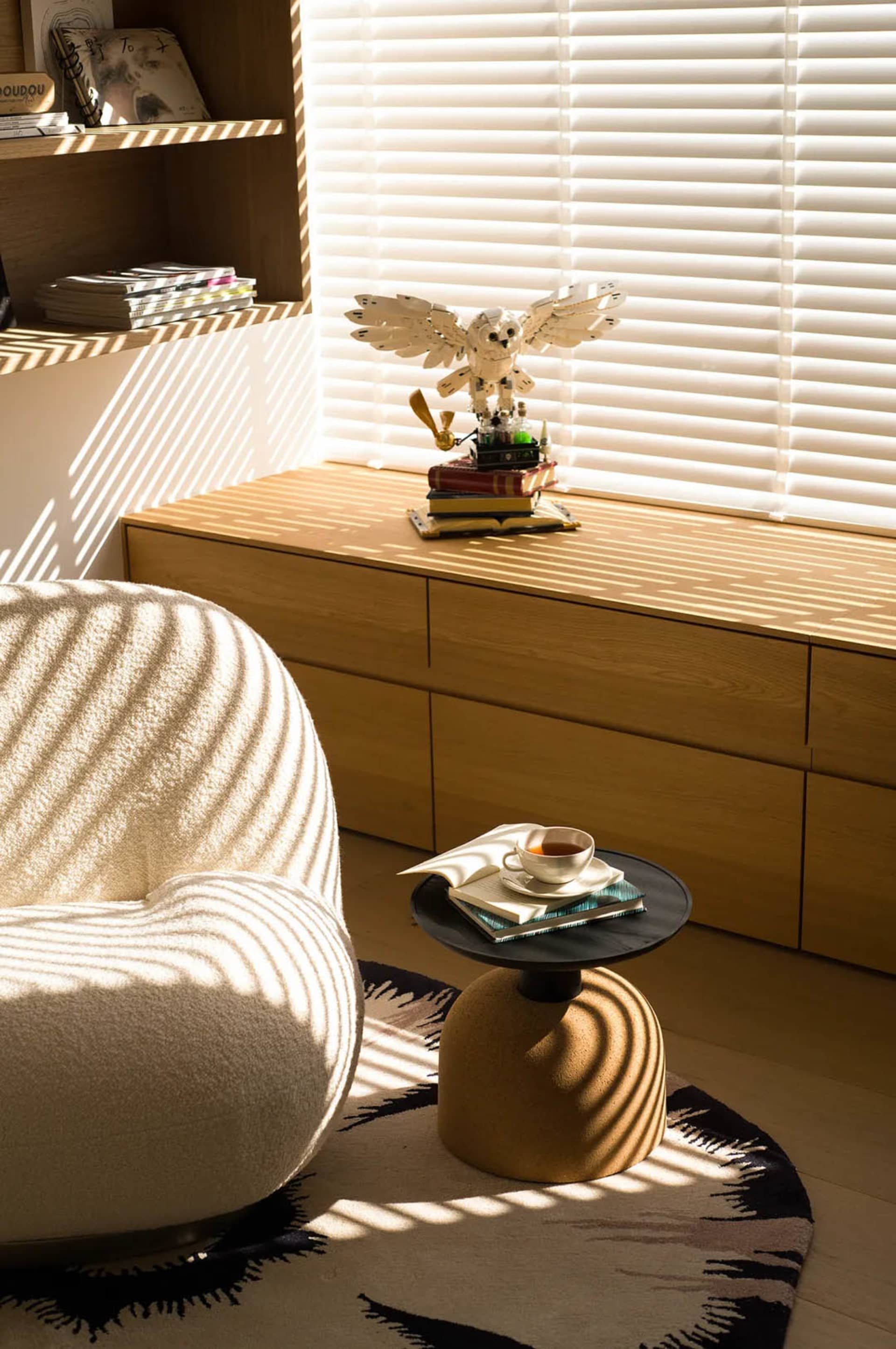 A well-lit living room with a white chair and wooden cabinet, creating a bright and inviting atmosphere