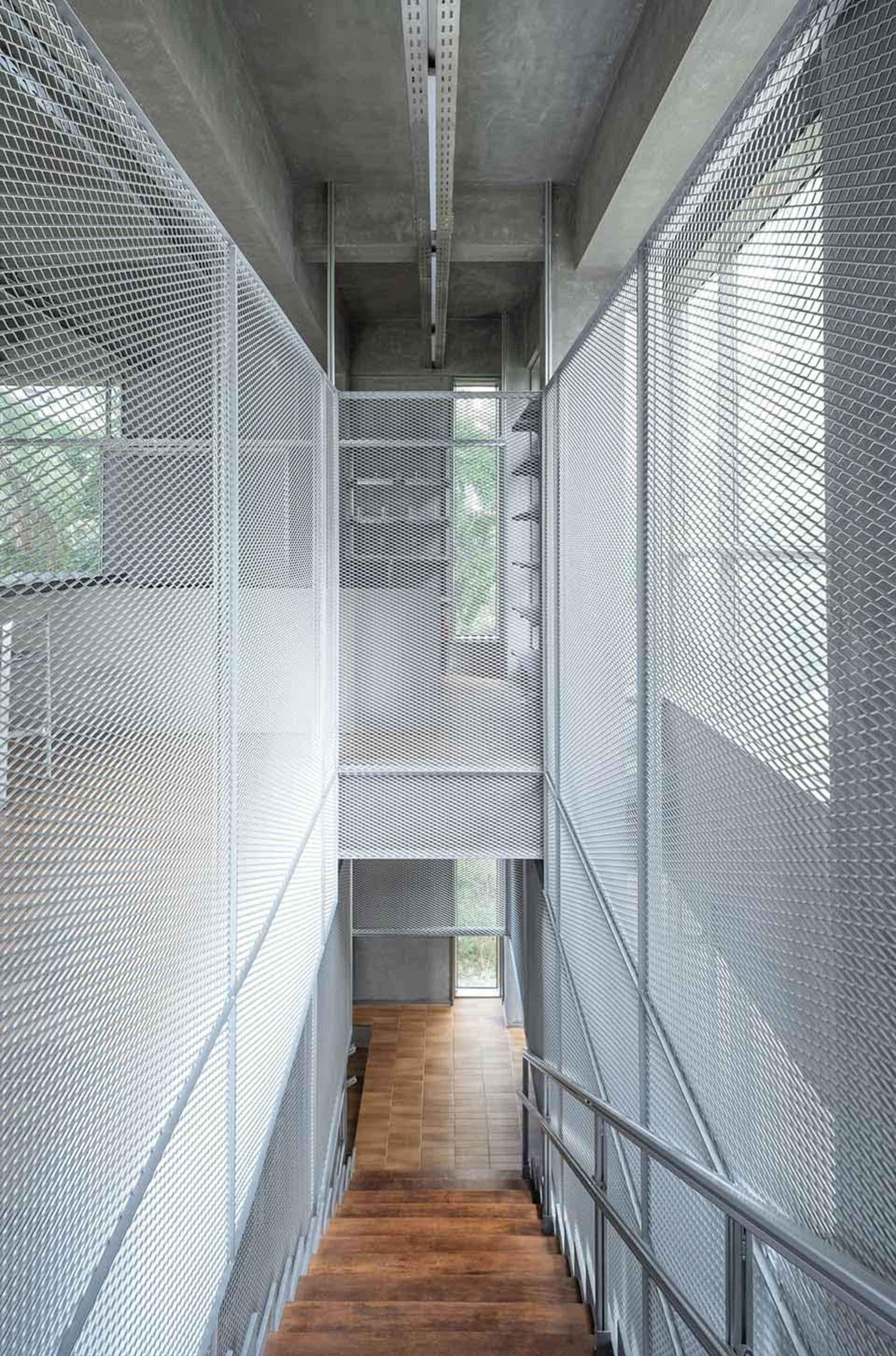 A modern stairwell with a glass wall and metal railing, set against a concrete building structure