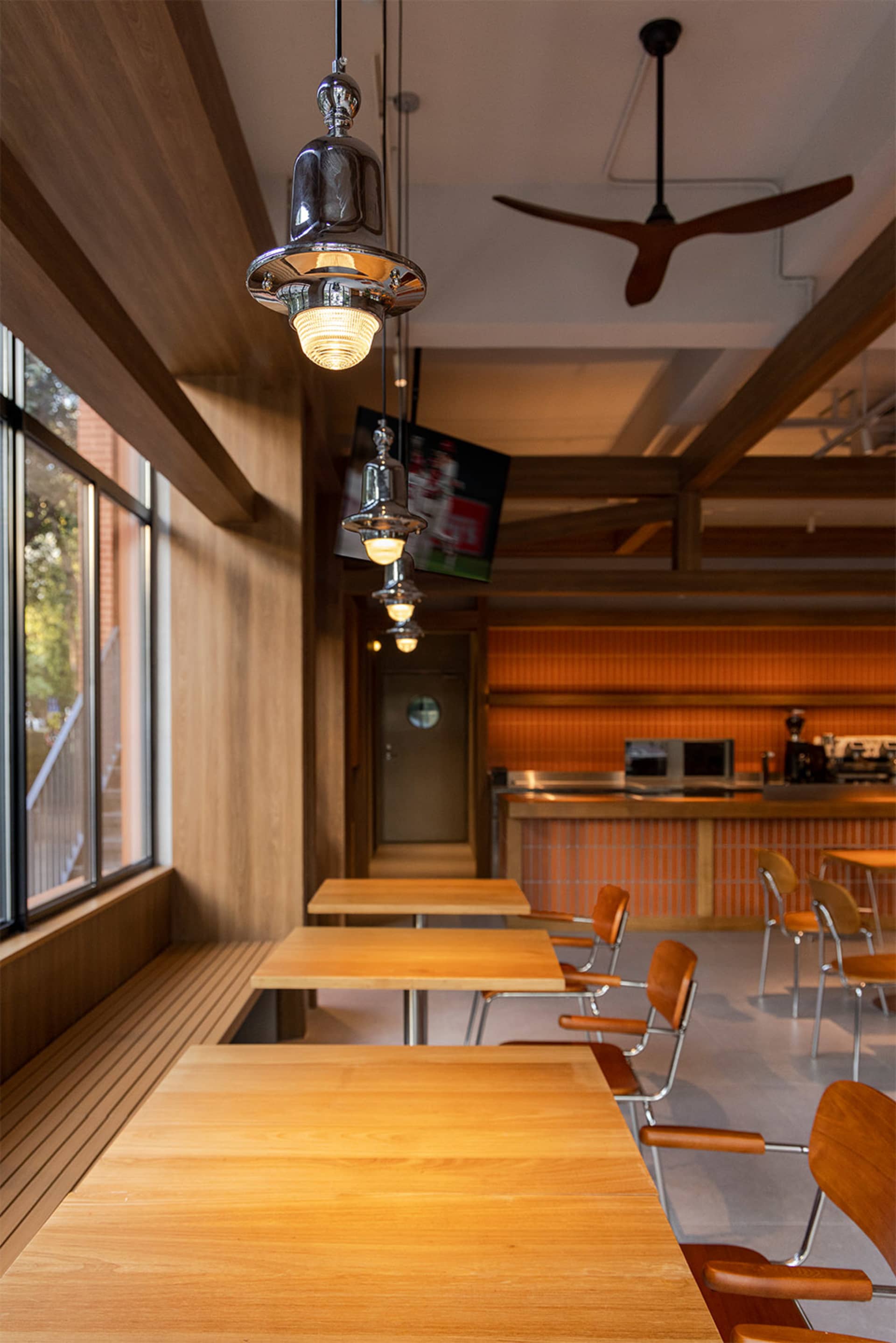 Warm and inviting dining space with wooden tables, chairs, and a TV, surrounded by natural light