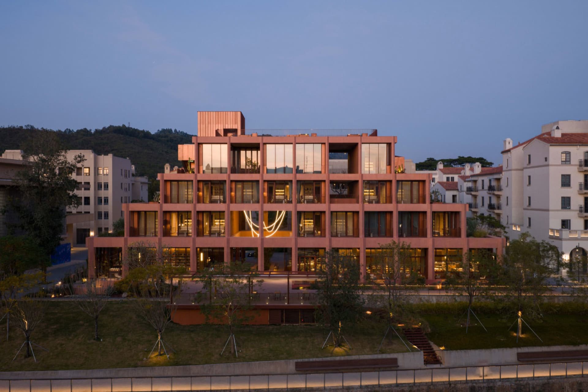 A large, multi-story building with a pink facade, featuring a mix of architectural styles, wood, and glass, and natural light streaming in through the windows