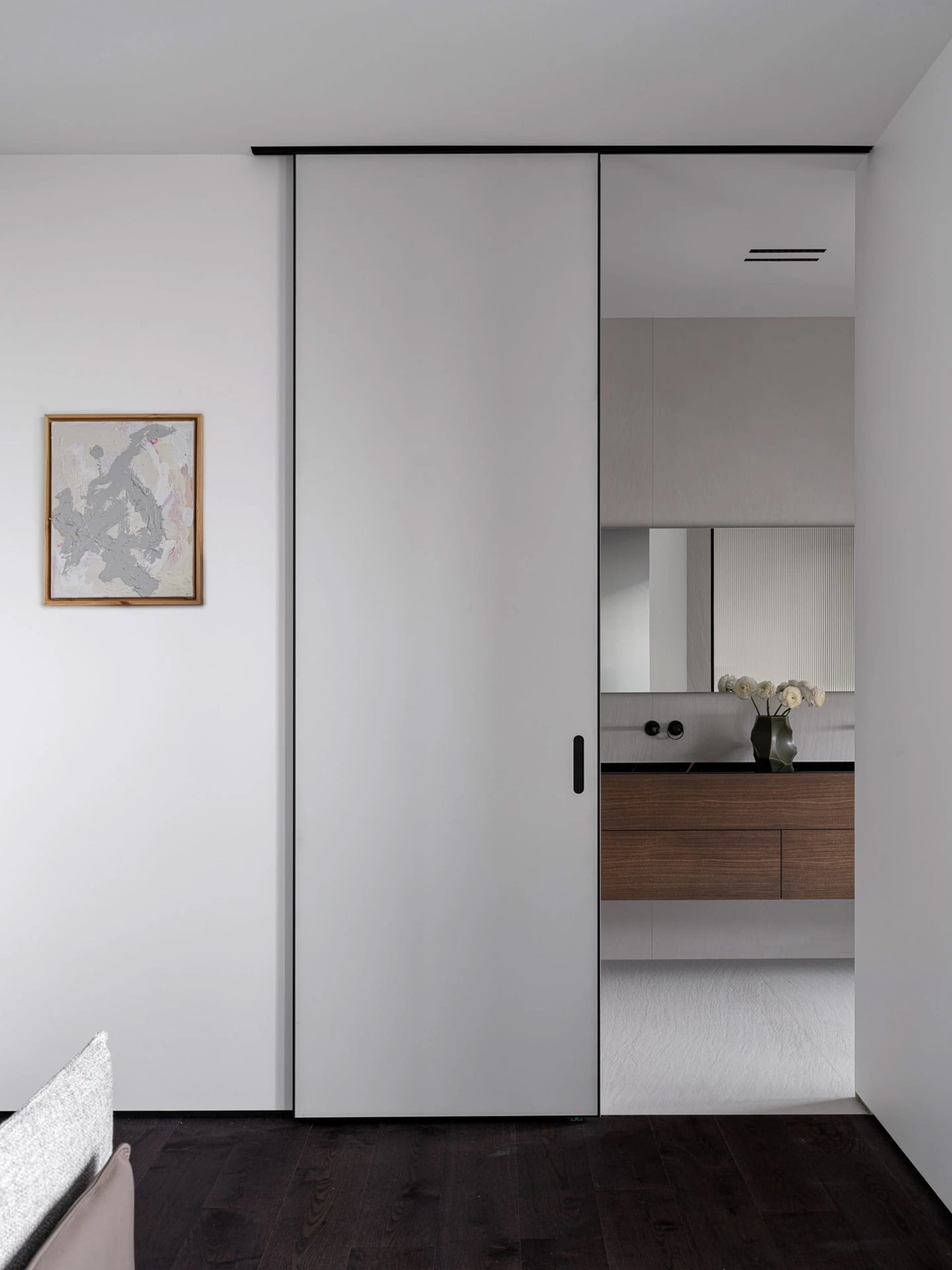 Modern bathroom with a white door, sink, and vase with flowers on the counter, under bright and inviting lighting