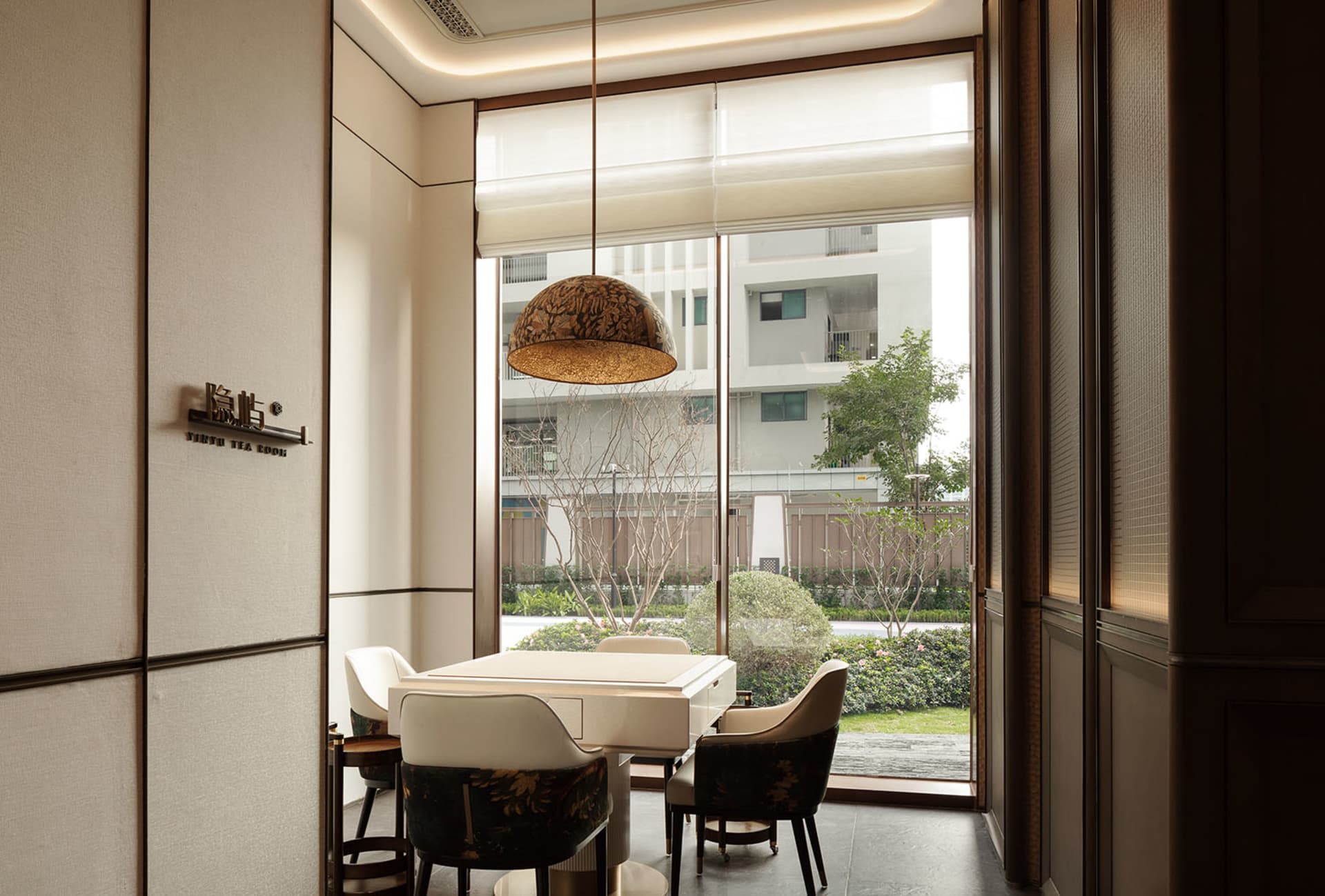 A modern living room with a white dining table and black chairs, surrounded by clean lines and minimalistic design elements, with natural light streaming in through a large window