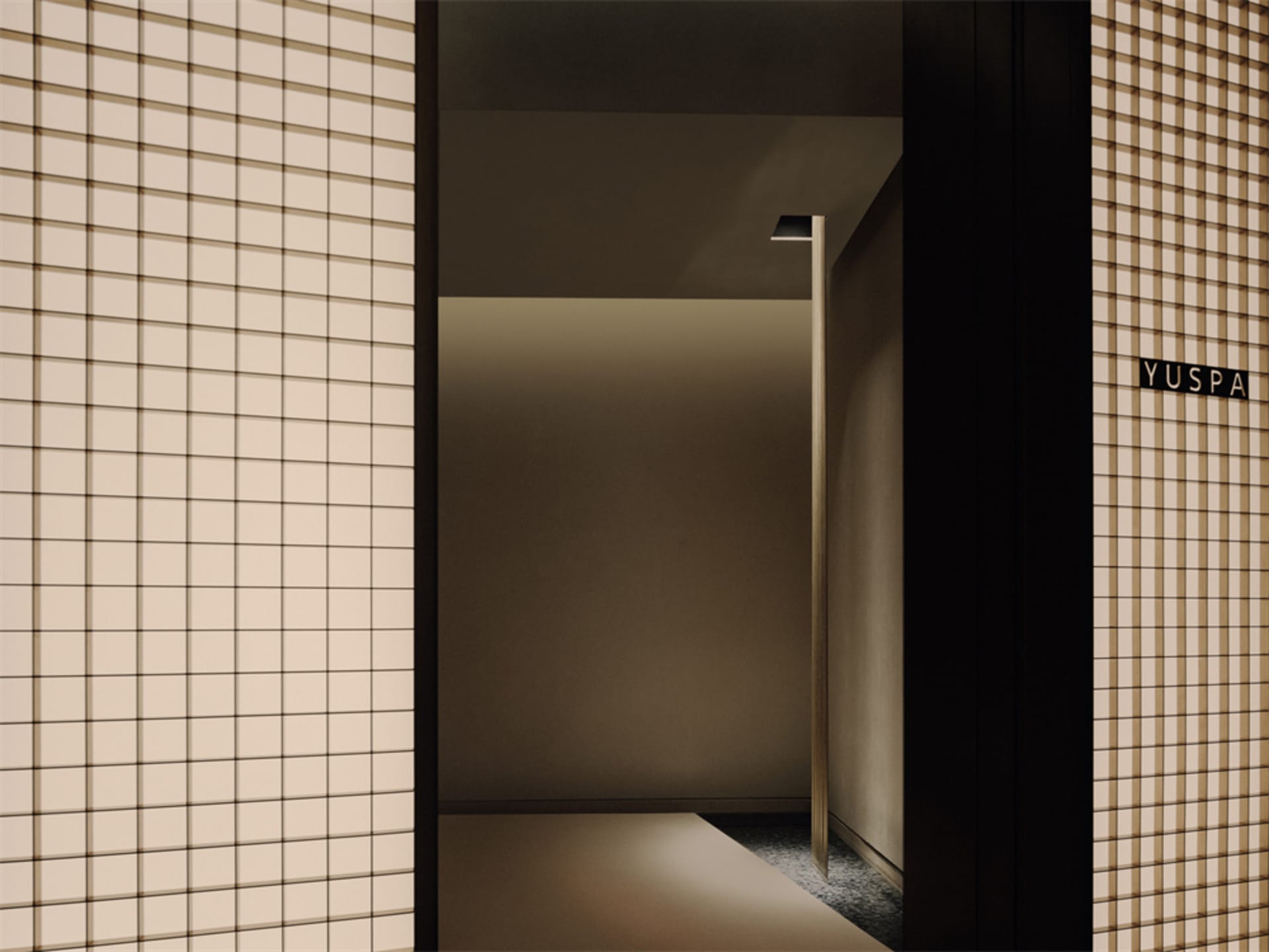 Dimly lit residential hallway with an open doorway and a light fixture on the wall