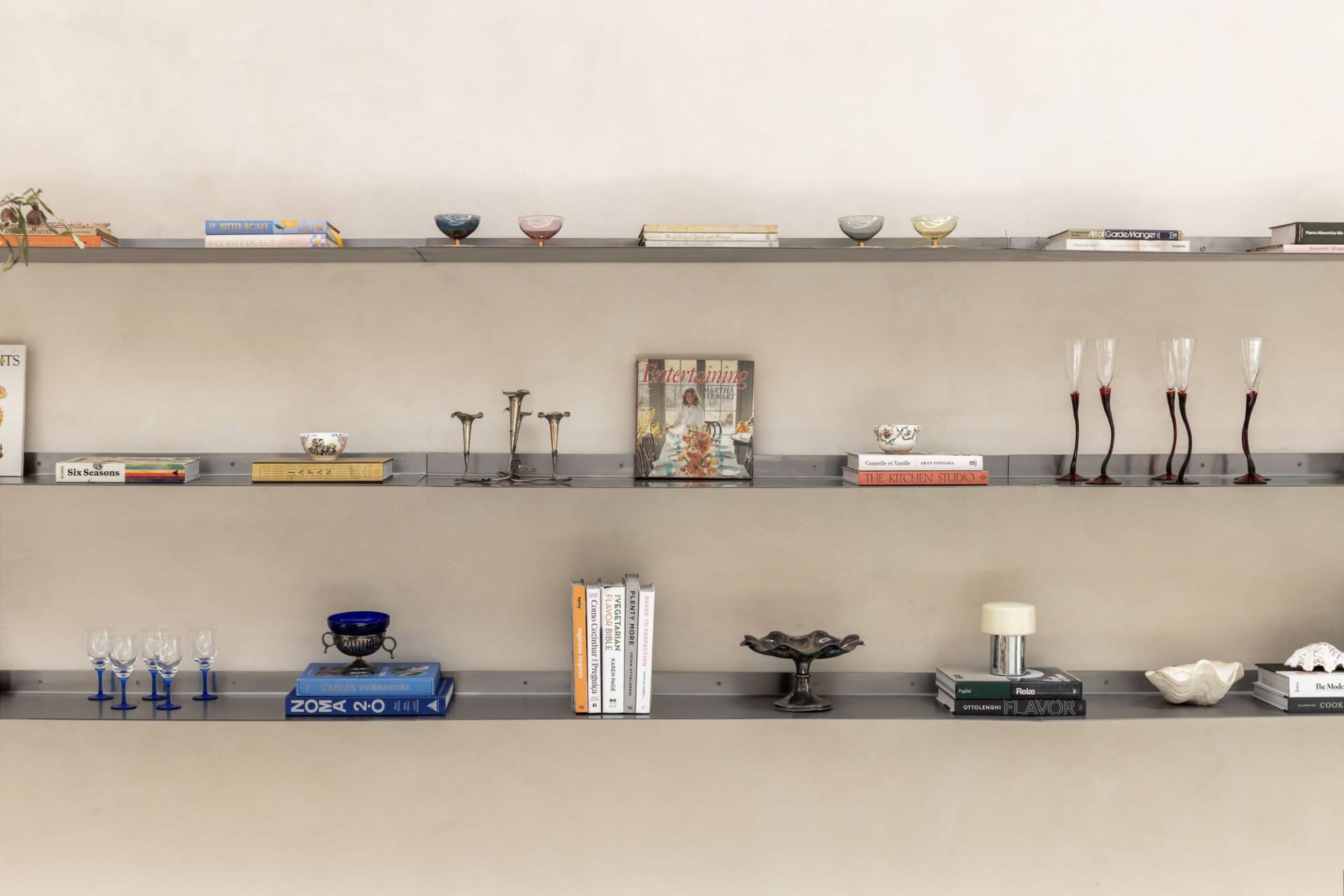 A cozy bookshelf filled with various books and decorative items, including vases, against a wall in a personal space