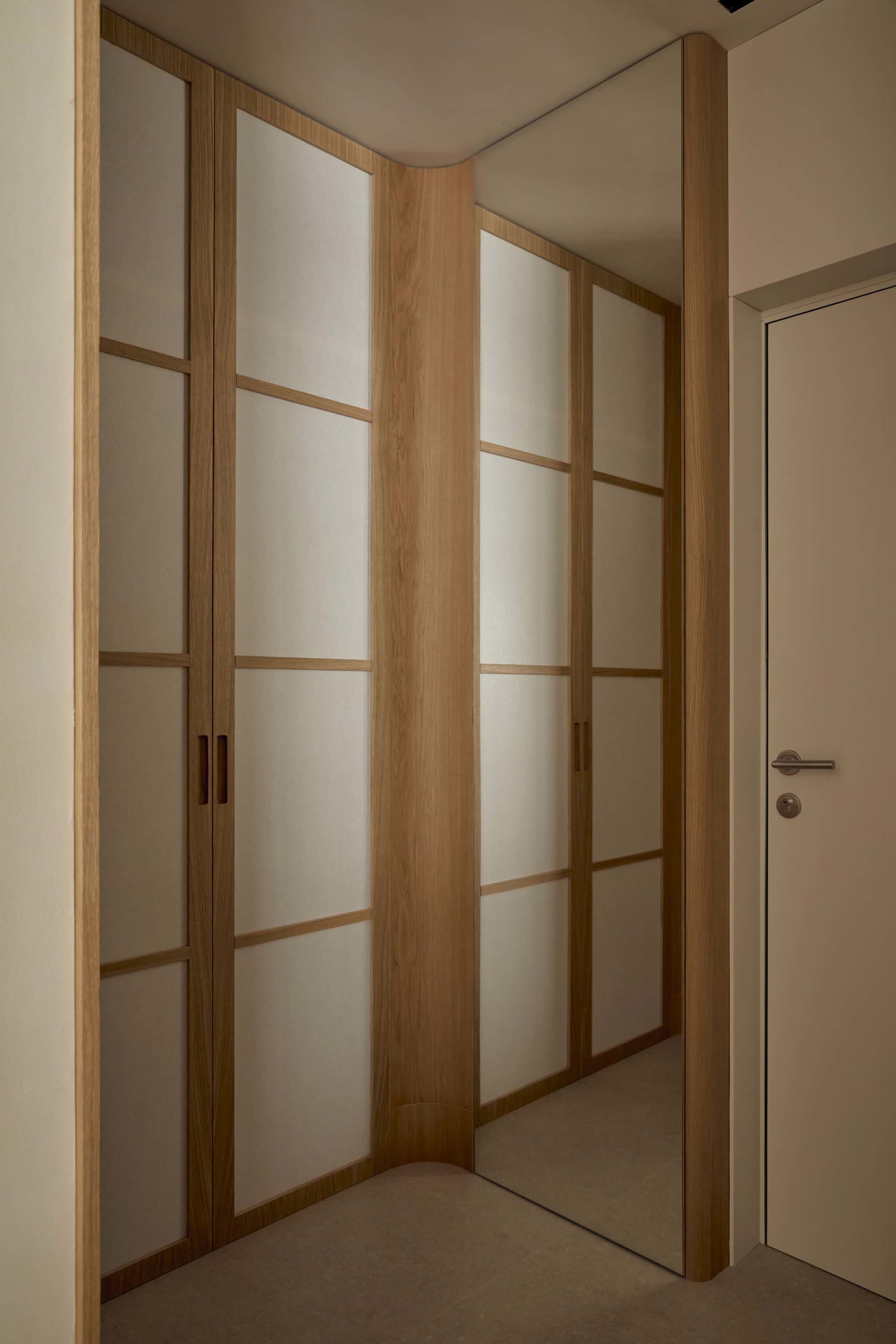 A dimly lit bedroom with a wooden door and cabinet, featuring a simple and functional style with a focus on wood elements
