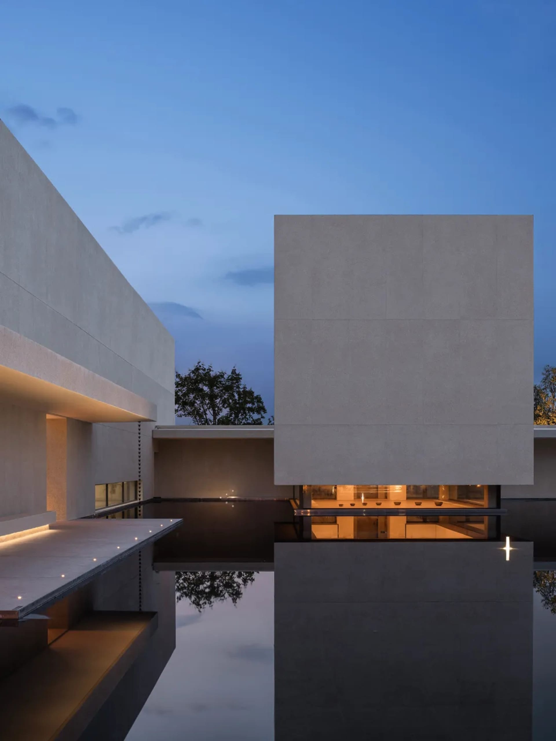 A large, modern building with a concrete exterior and a reflecting pool in front, surrounded by well-lit, inviting atmosphere