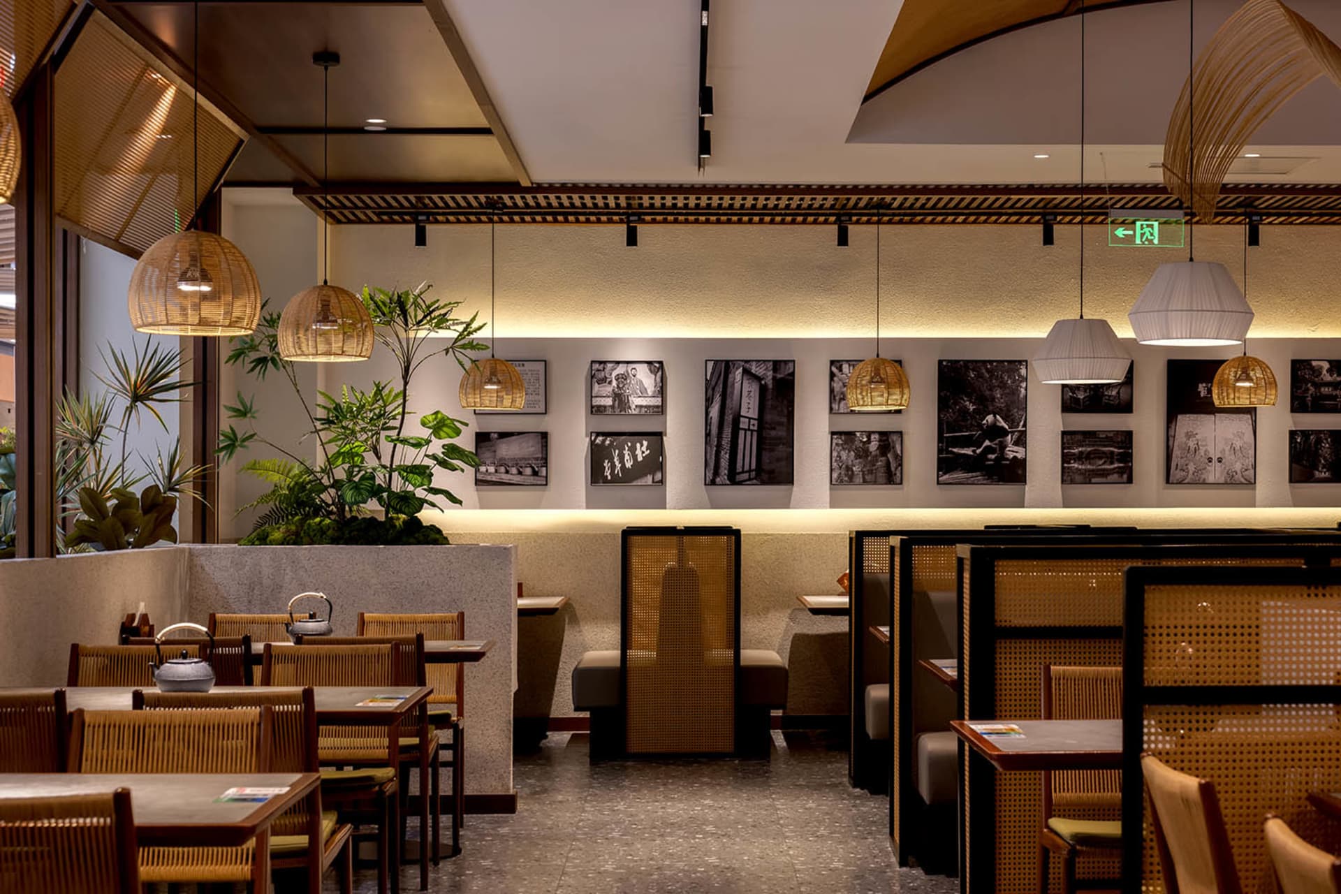 A well-lit restaurant interior with modern wood and metal elements, tables, chairs, and potted plants