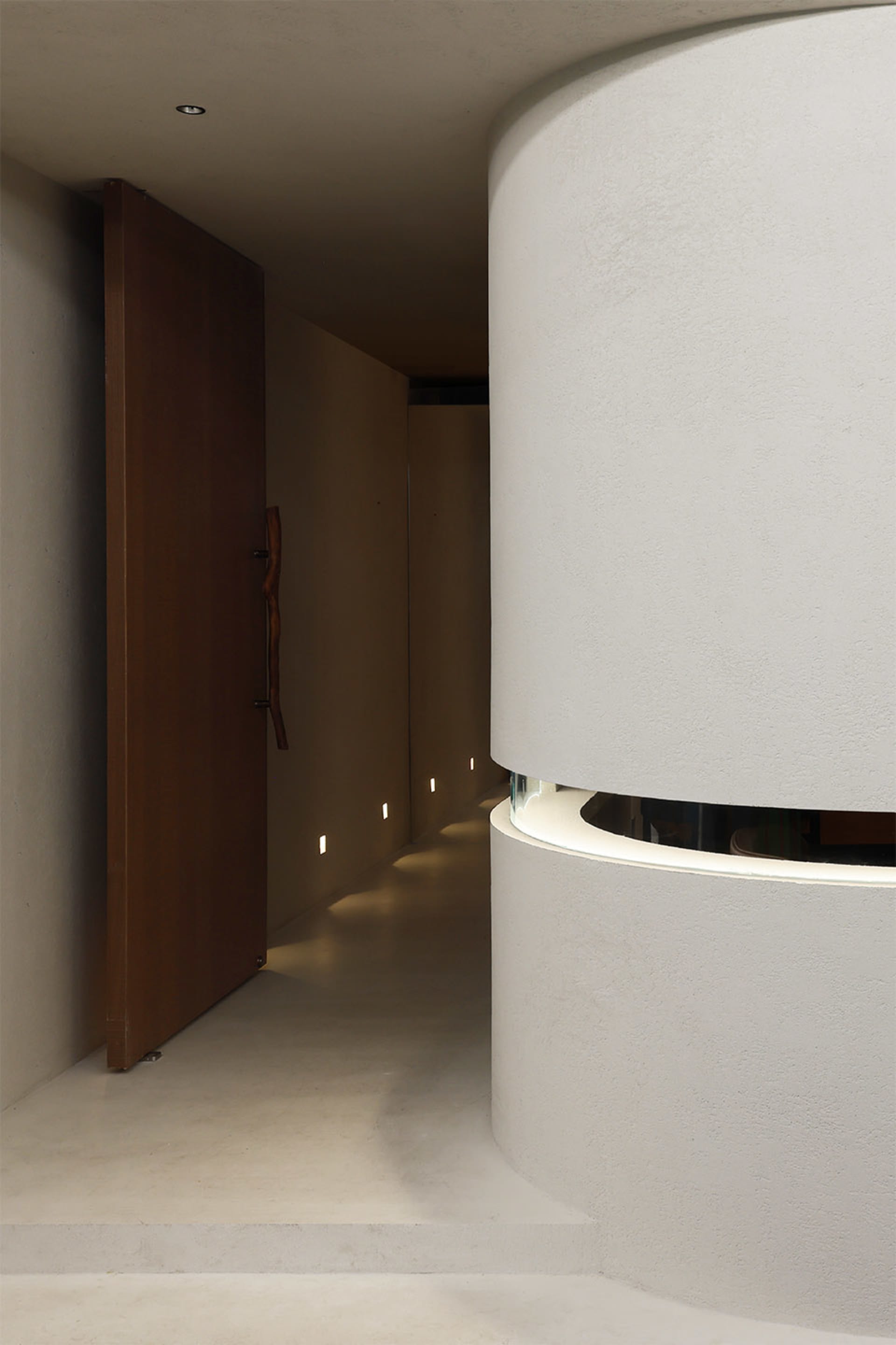 A bright and inviting hallway with a white color scheme, curved design, and concrete walls, illuminated by lights
