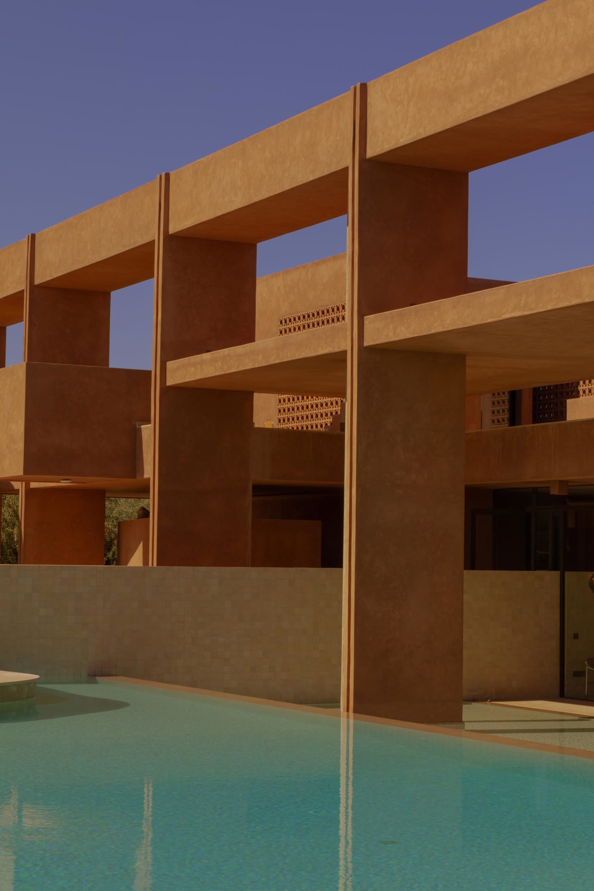 A modern house with a swimming pool surrounded by a stone wall, featuring a unique design with brown and orange colors, creating a relaxing and inviting atmosphere