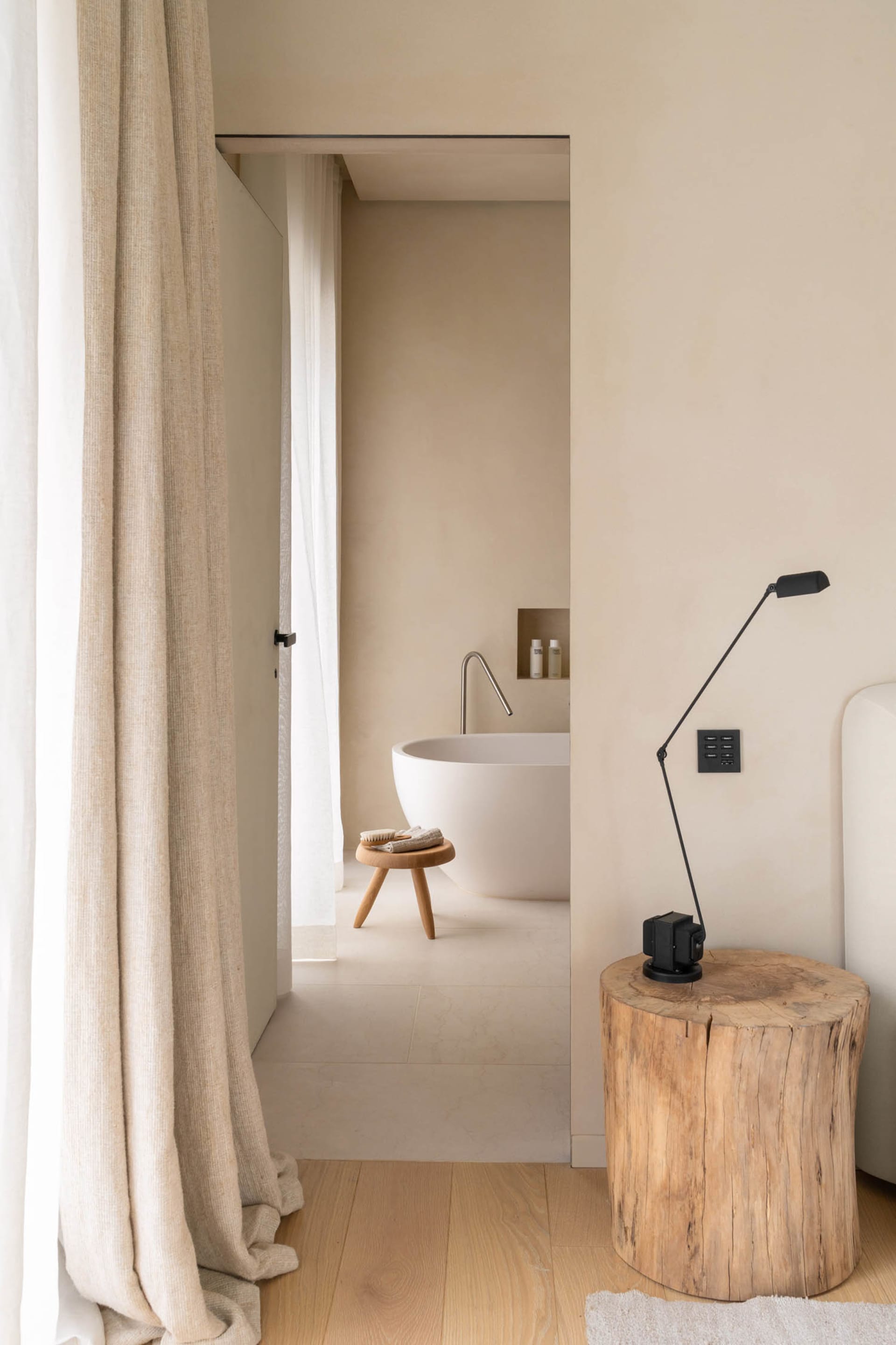 Bathroom with a white tub, sink, and toilet, set against a wooden floor and dimly lit for a cozy atmosphere