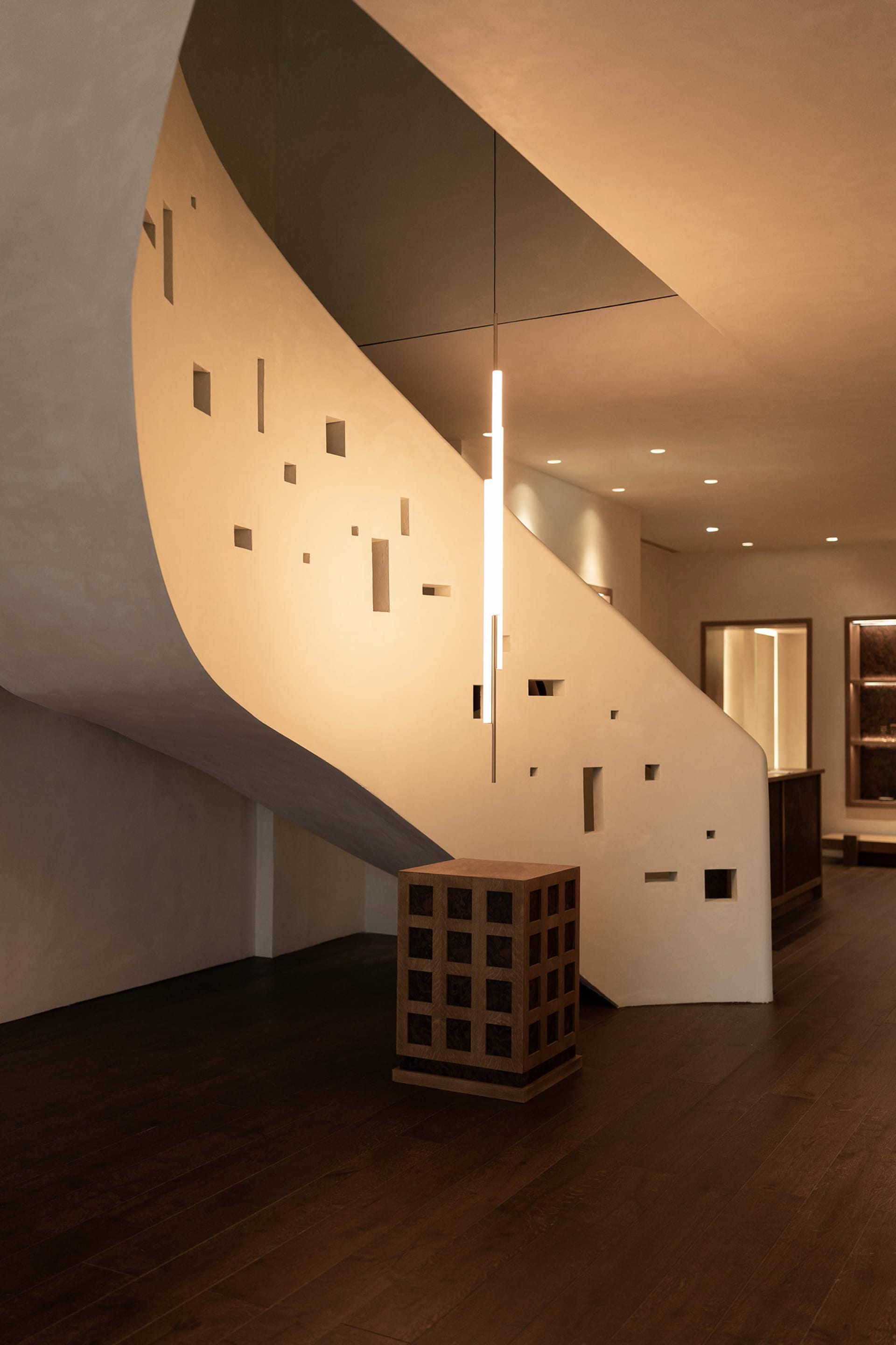 A bright and inviting staircase with a modern wooden design and a metal light fixture hanging from the ceiling