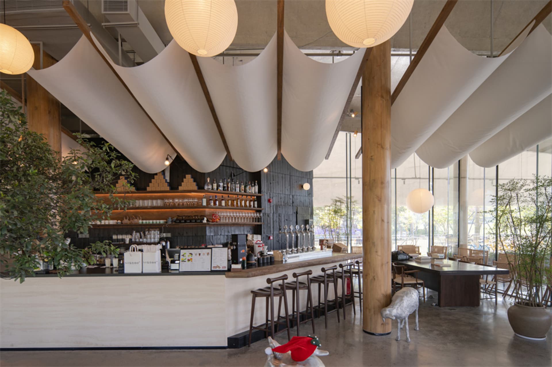 A modern restaurant interior with a bar, dining area, and warm soft lighting, featuring a mix of wood and metal elements, with various decorative items and a cozy atmosphere