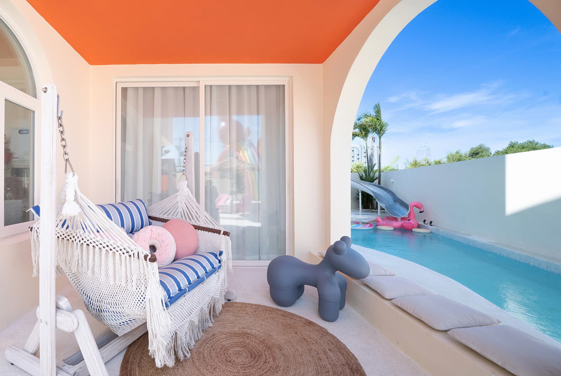 Modern living room with a blue and white color scheme, a pool in the backyard, and a patio with a slide