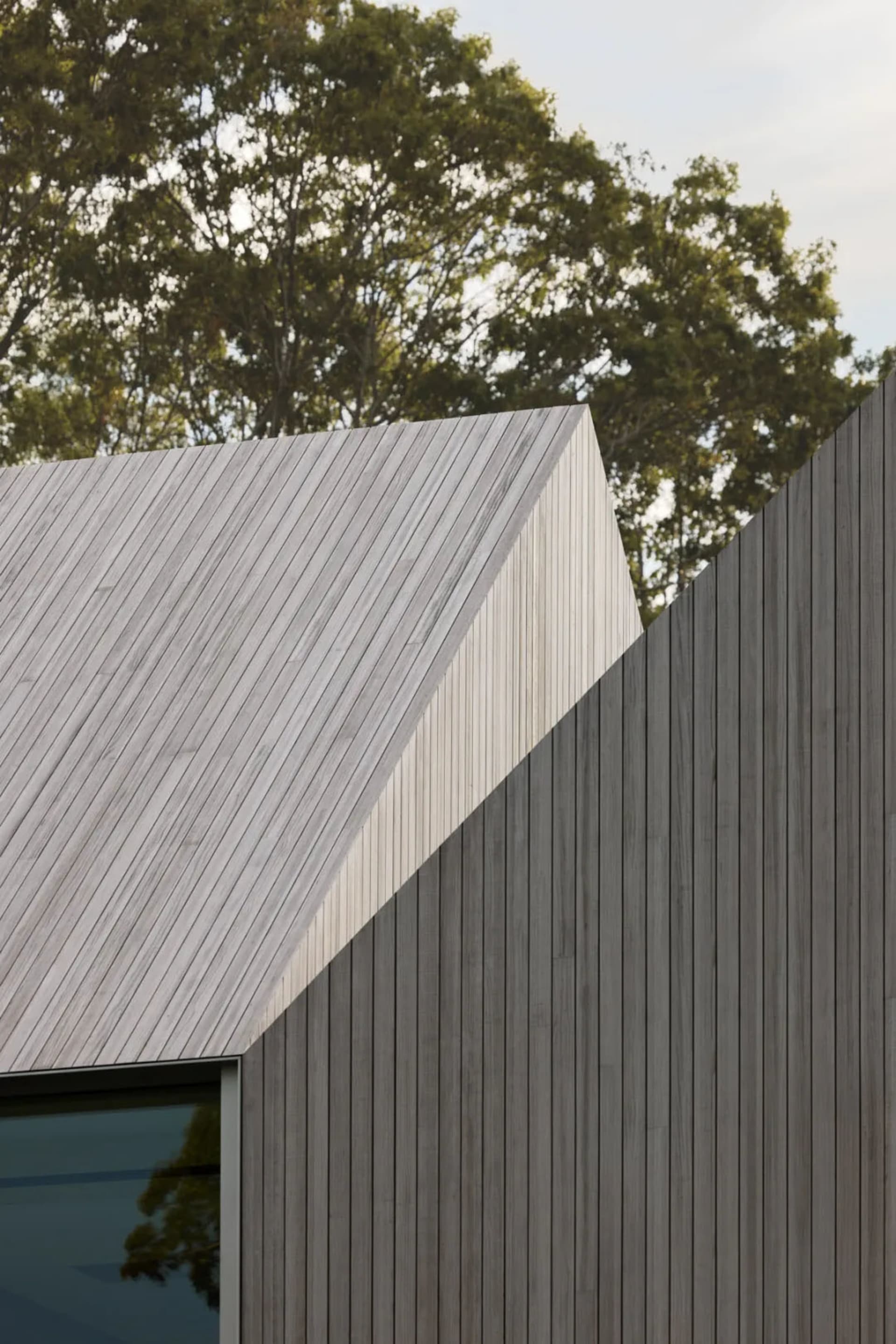 Photograph of a unique triangular house with a wooden exterior and a sloping roof, showcasing its architectural style