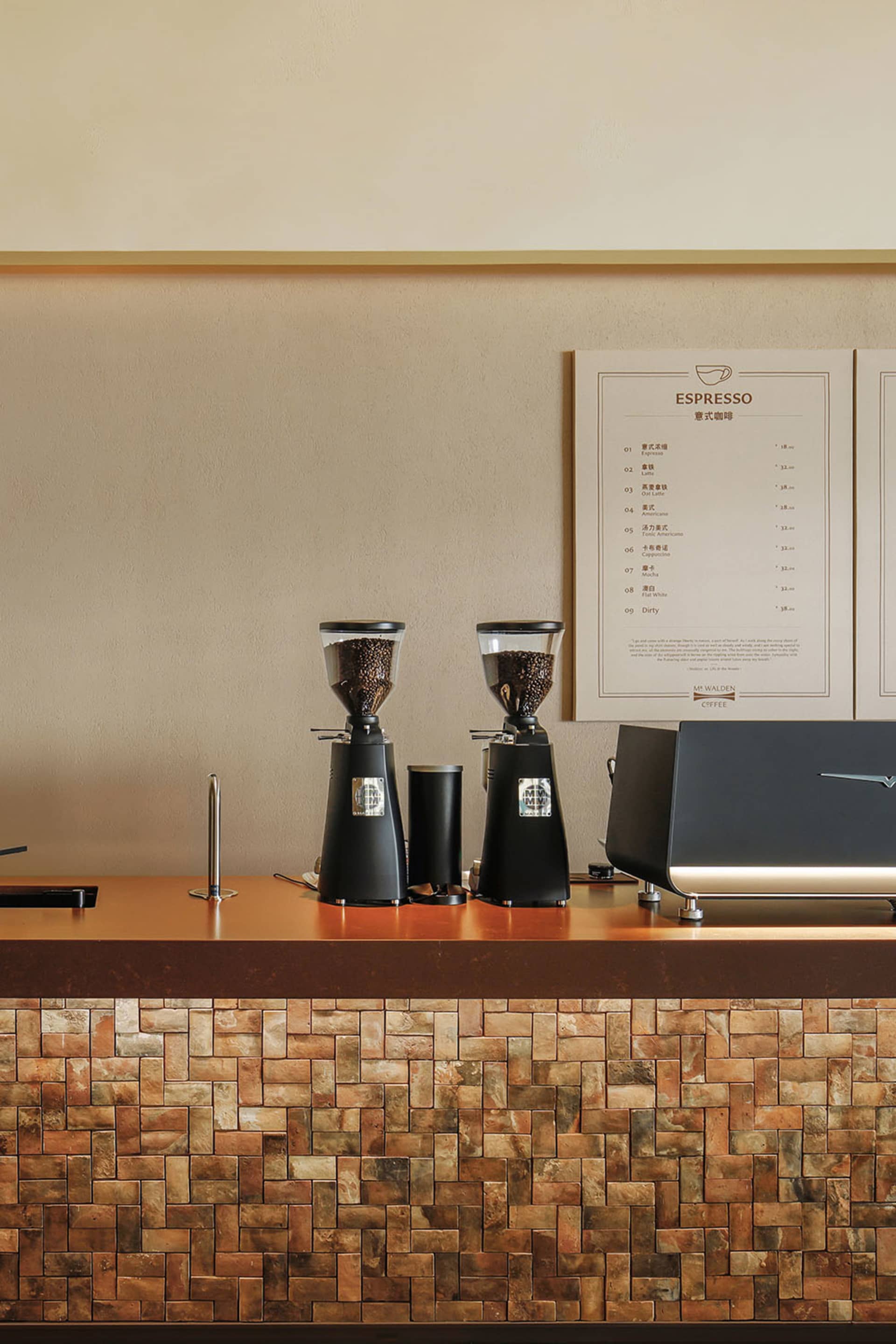 A cozy coffee shop with a counter displaying coffee-making equipment, including a grinder, surrounded by warm wood and metal accents, with soft lighting creating a welcoming atmosphere