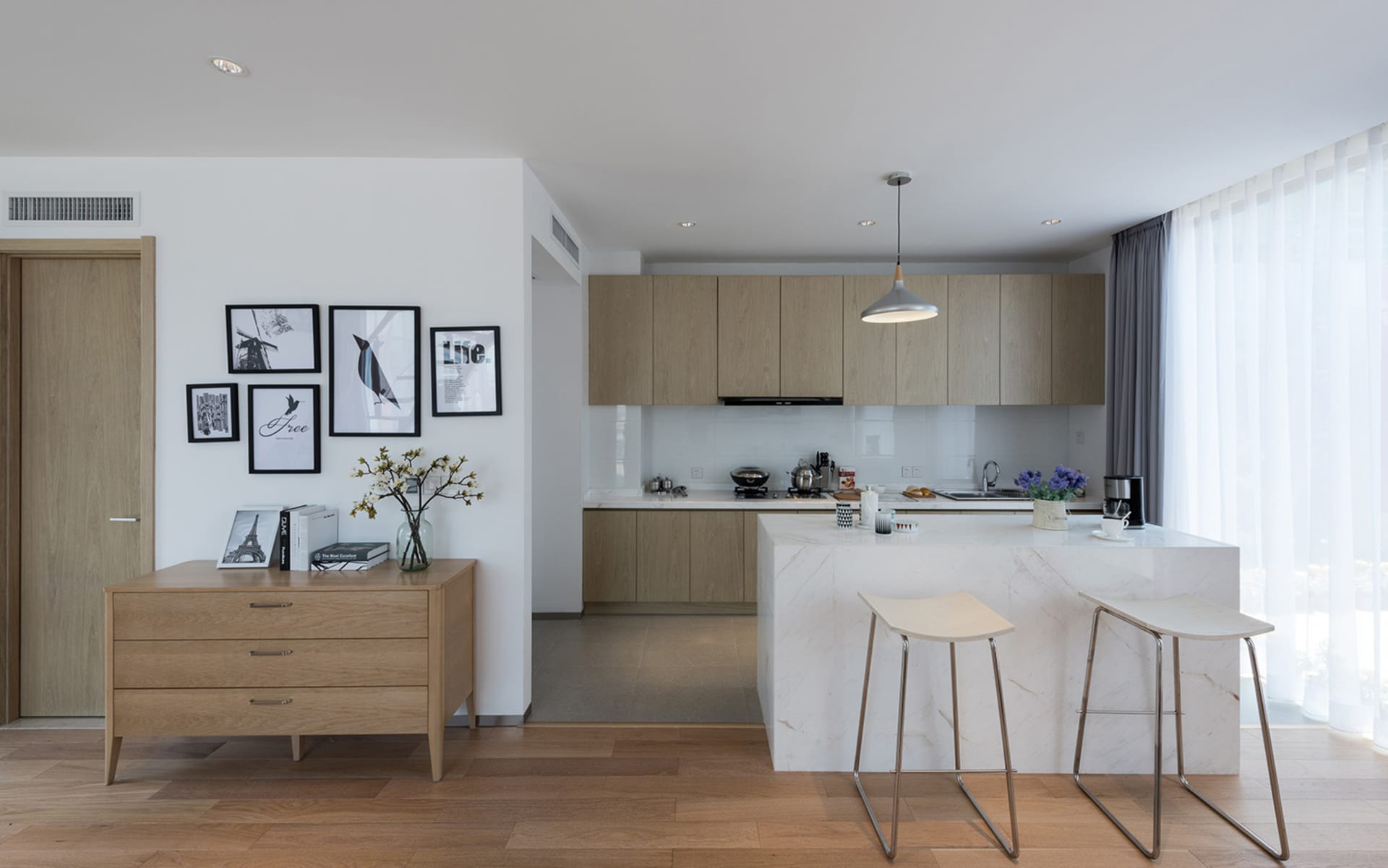 Bright and inviting modern kitchen and dining space with a marble countertop, wooden table, and black oven