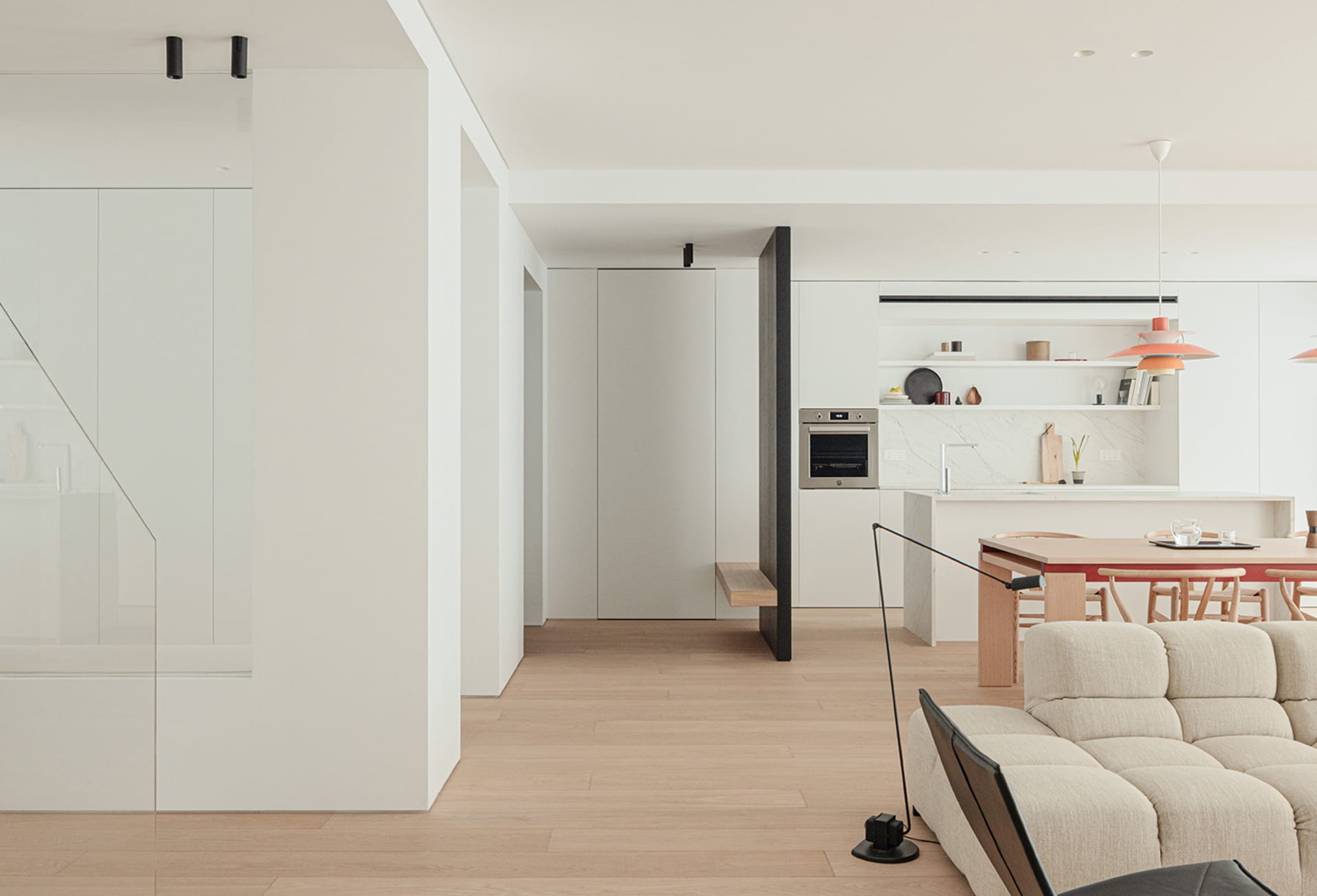 Modern kitchen and living space with white walls, black appliances, and sleek furniture