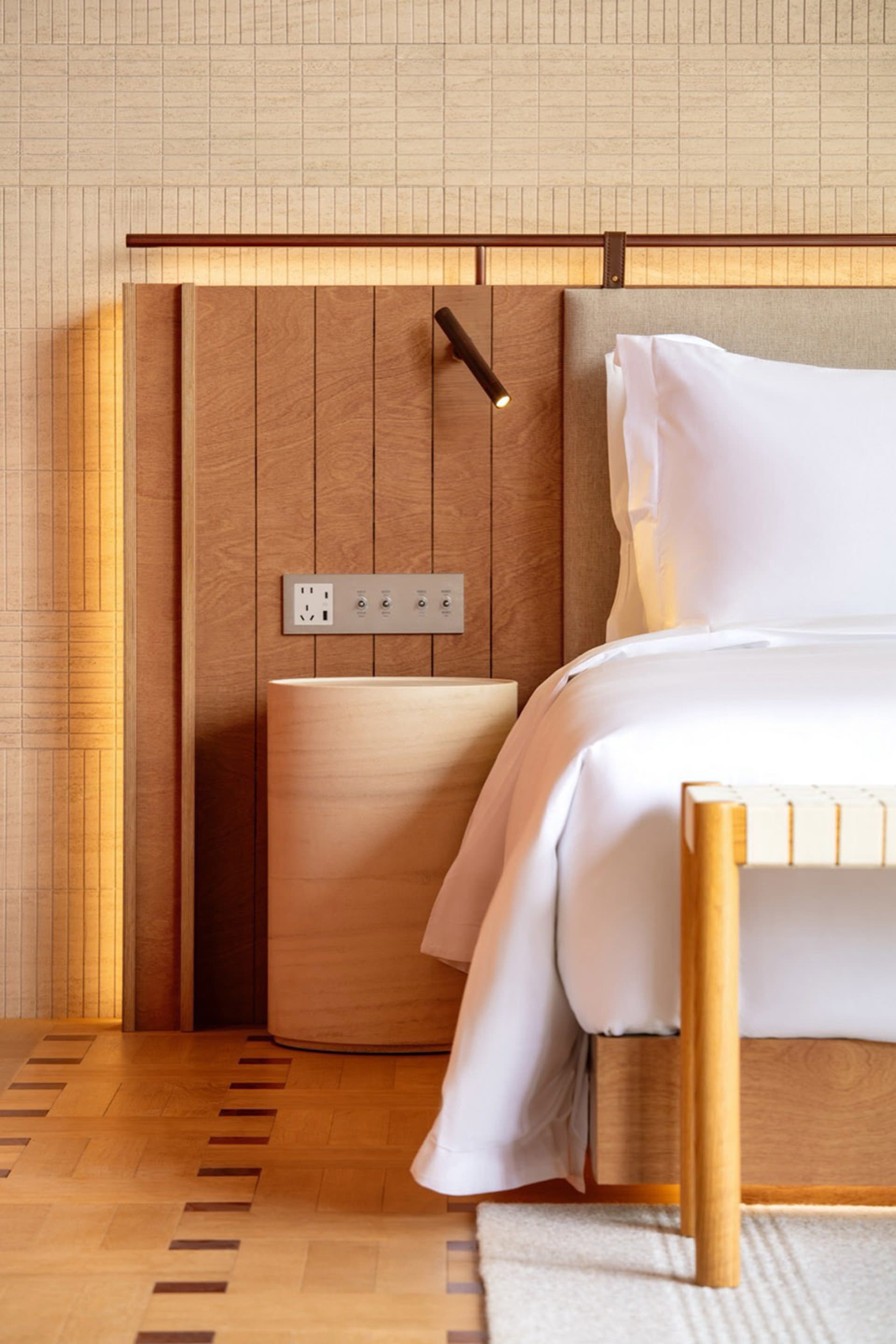 Cozy modern bedroom with a wooden floor, a wooden headboard, and a white comforter on a bed, lit by dim lighting