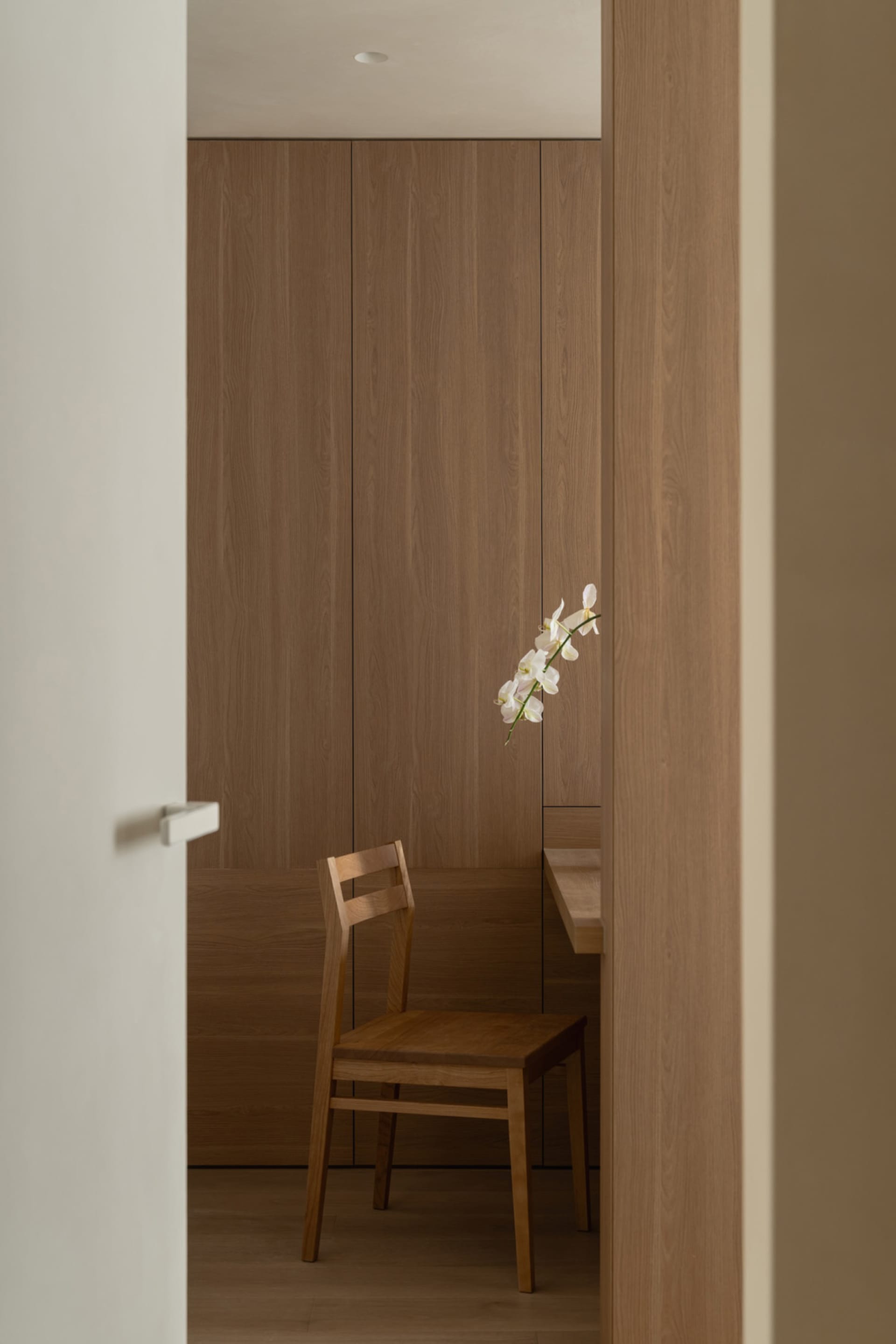 Dining room with wooden walls and table, a wooden chair, and a vase with flowers adding a touch of elegance