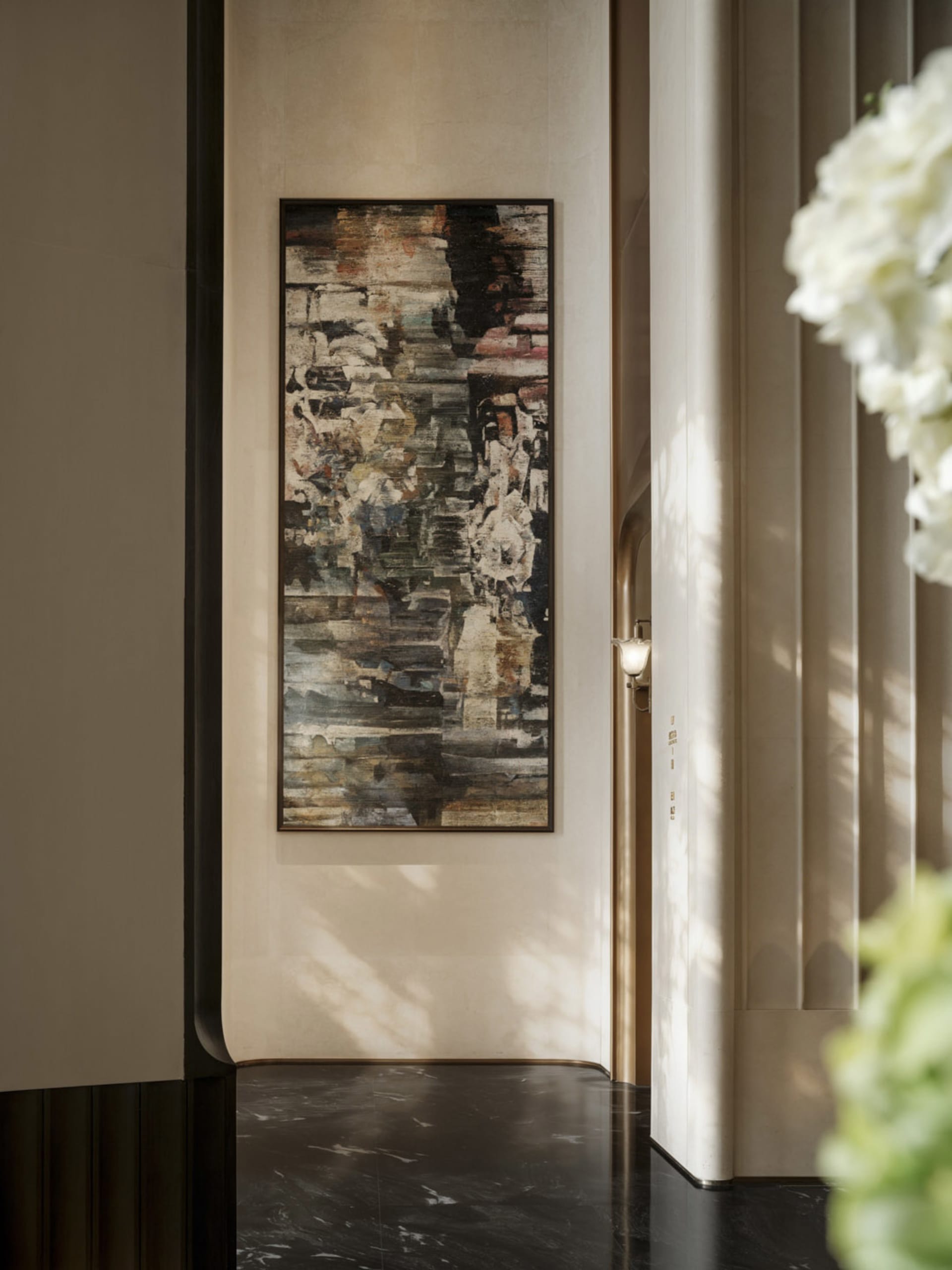 A modern room with a large black and white painting on the wall, surrounded by a white color scheme and subtle shadows