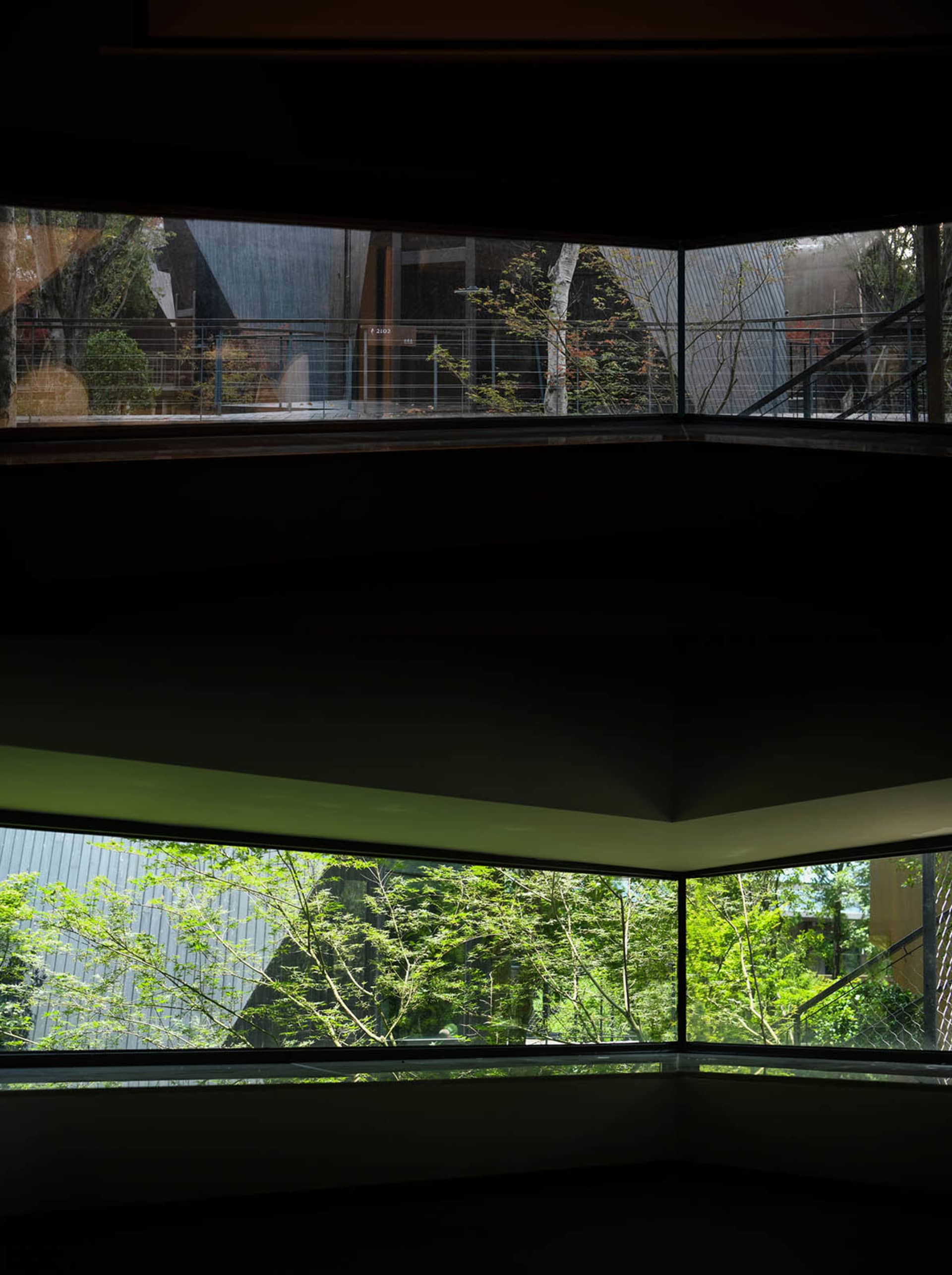 A serene photograph of a modern building with a large window and a view of the surrounding forest