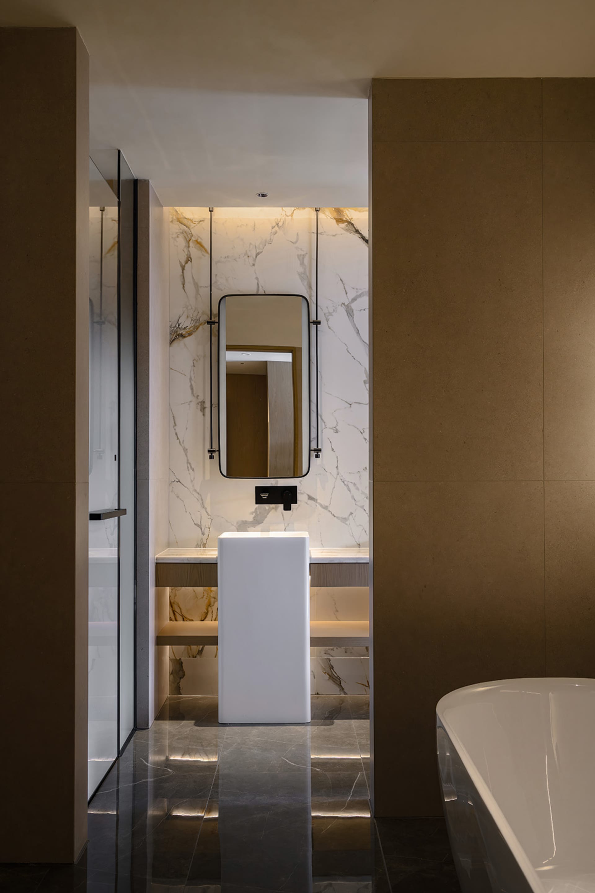 Bathroom with a white bathtub, toilet, marble countertop, and sink, set against a brown wall with dim lighting