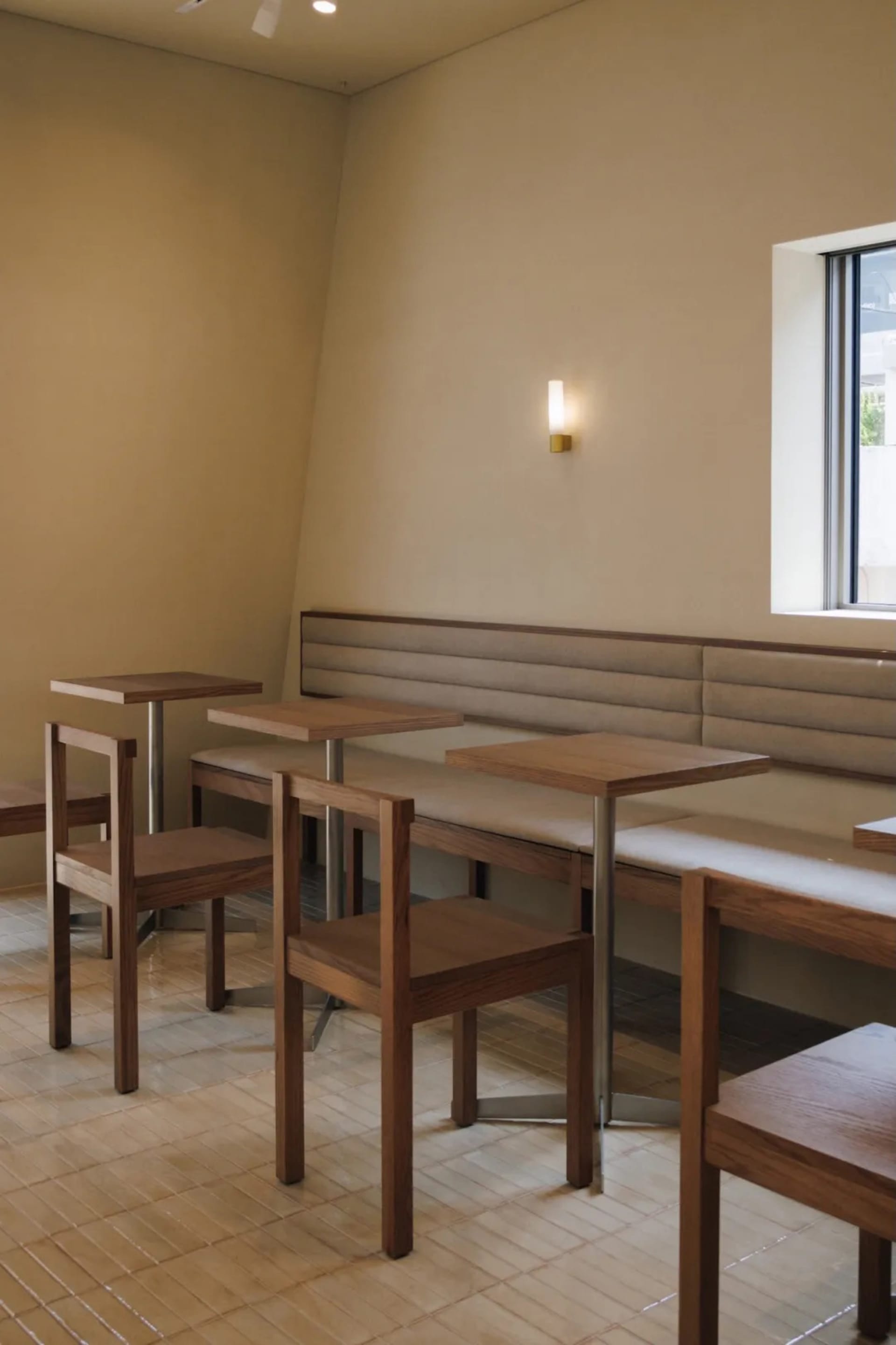 Cozy dining space with a wooden floor, white walls, and natural light from a window, featuring a bench and chairs around a dining table